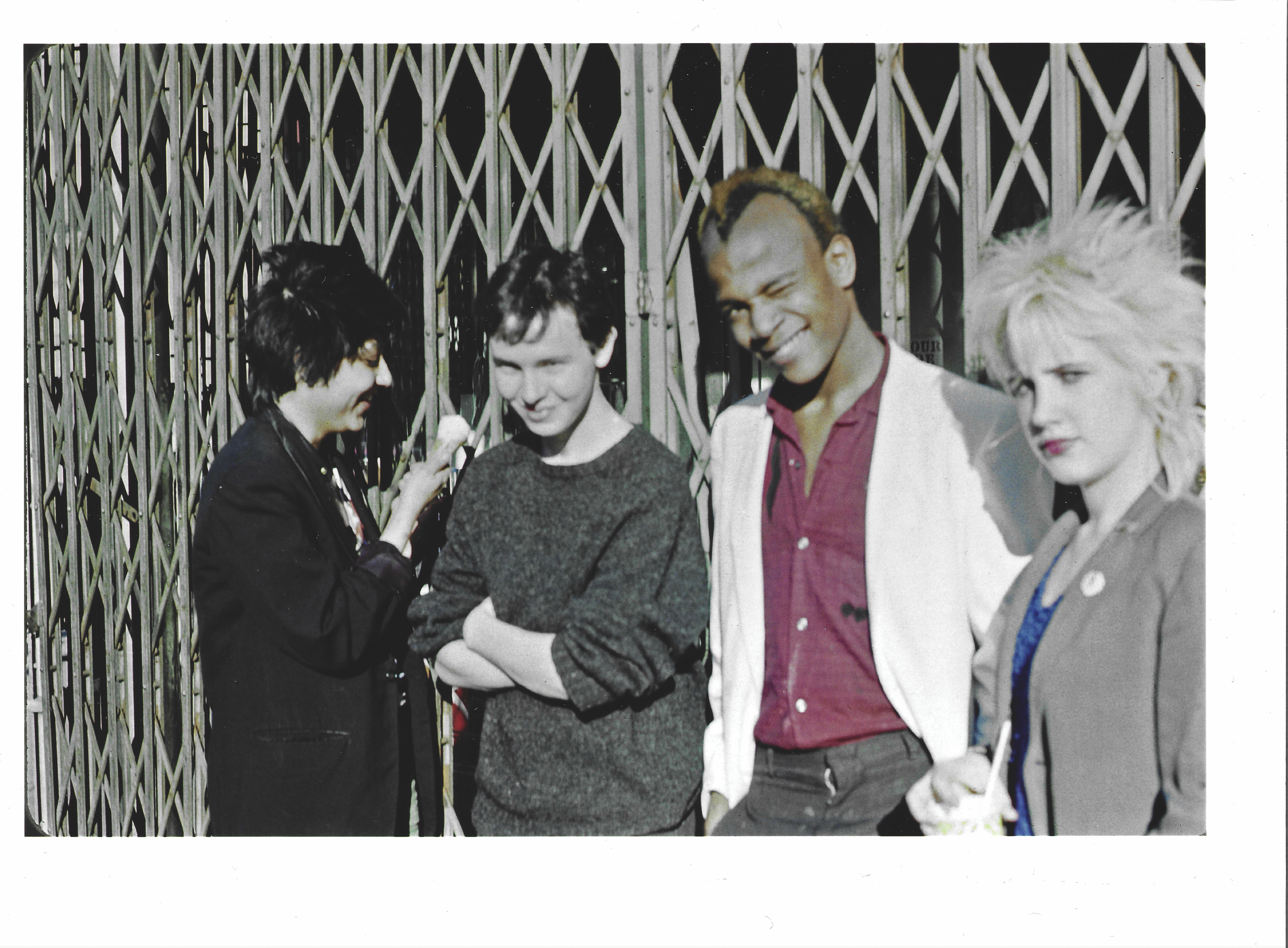 Four people standing in front of a metal grill pattern.