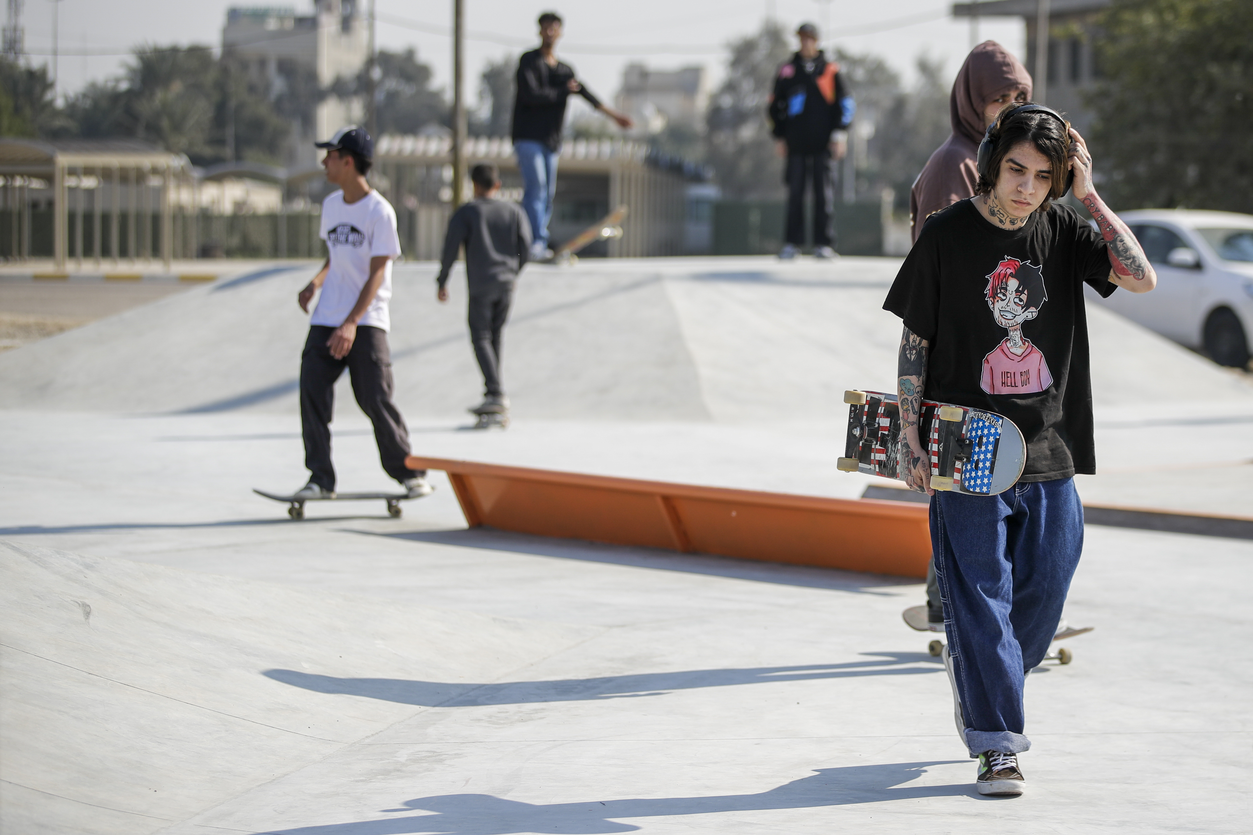 Diverse group of people skateboarding and standing at an outdoor skate park.