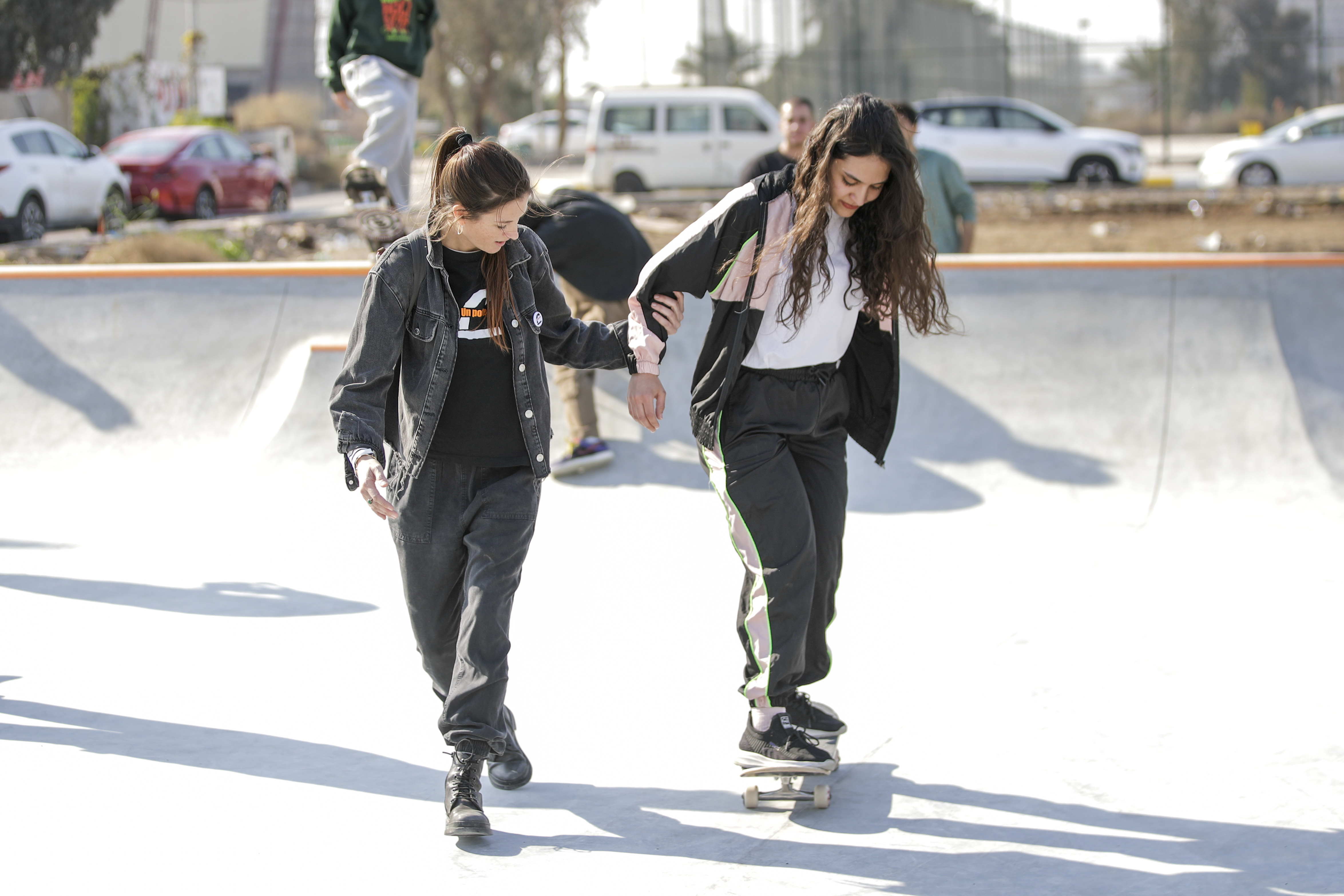 Two young people, a man and a woman, walking and interacting in an urban outdoor setting.
