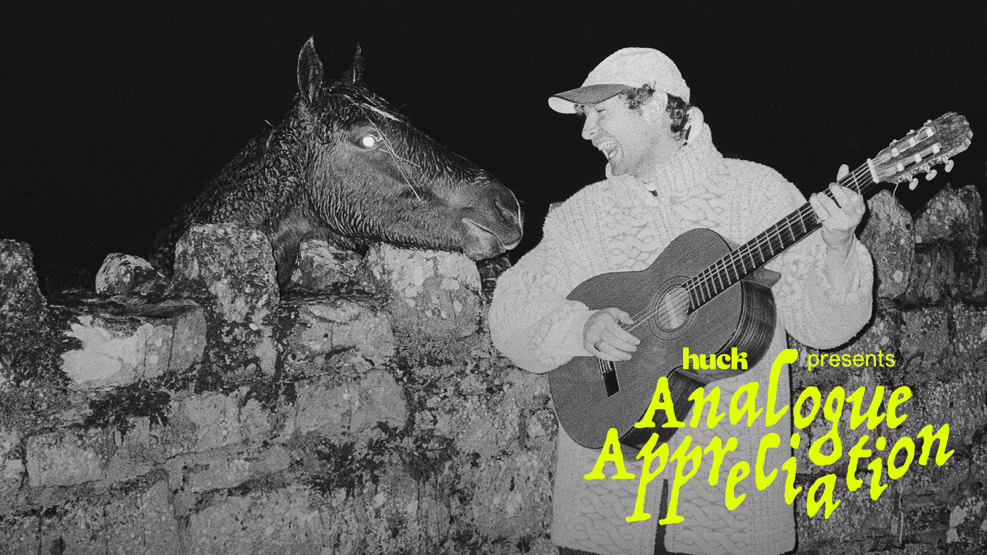 A man playing a guitar whilst a horse stands beside him in a rocky, moonlit landscape.
