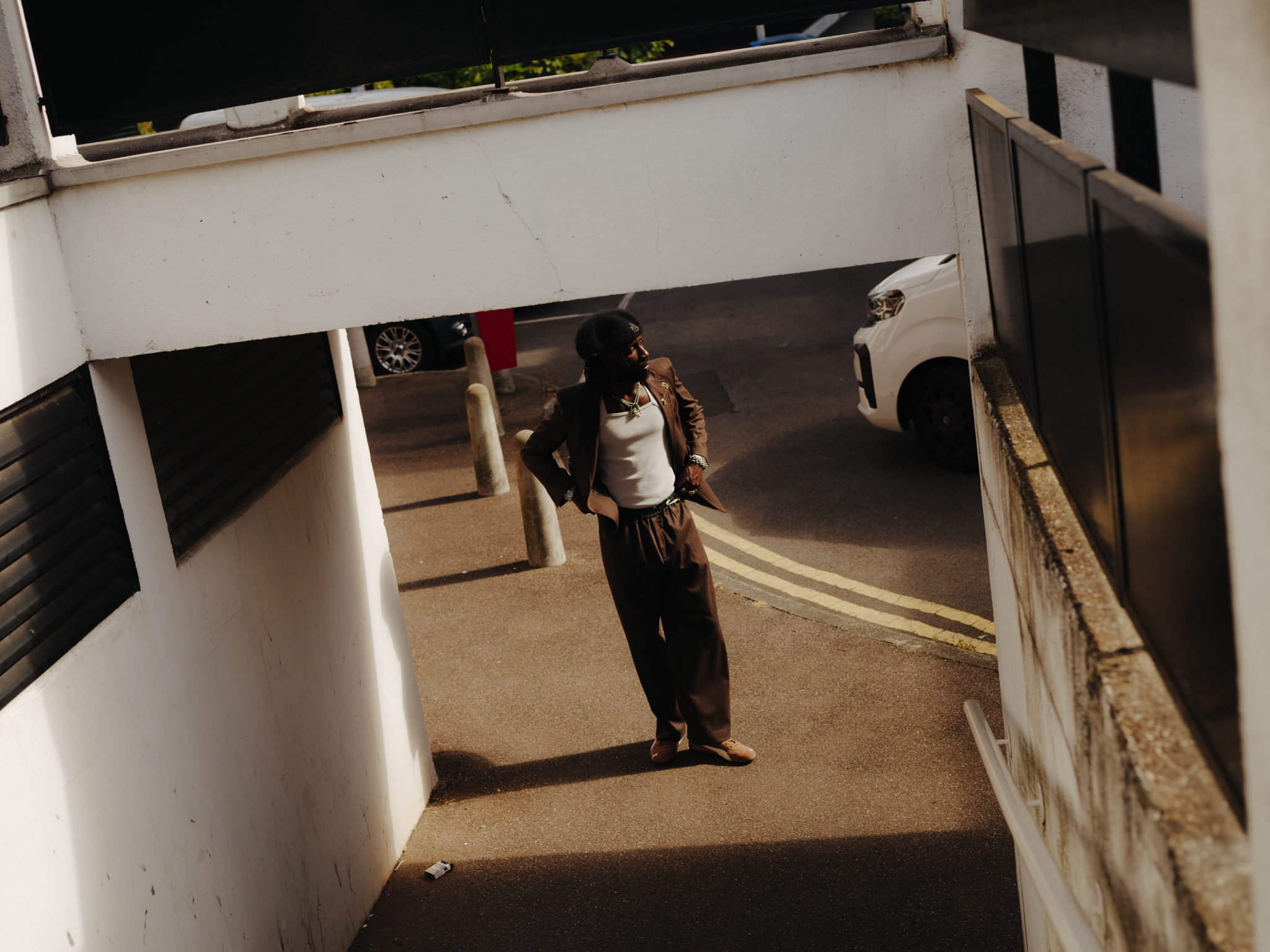 Person carrying white container on head walking through white-walled courtyard or building interior, viewed from above.