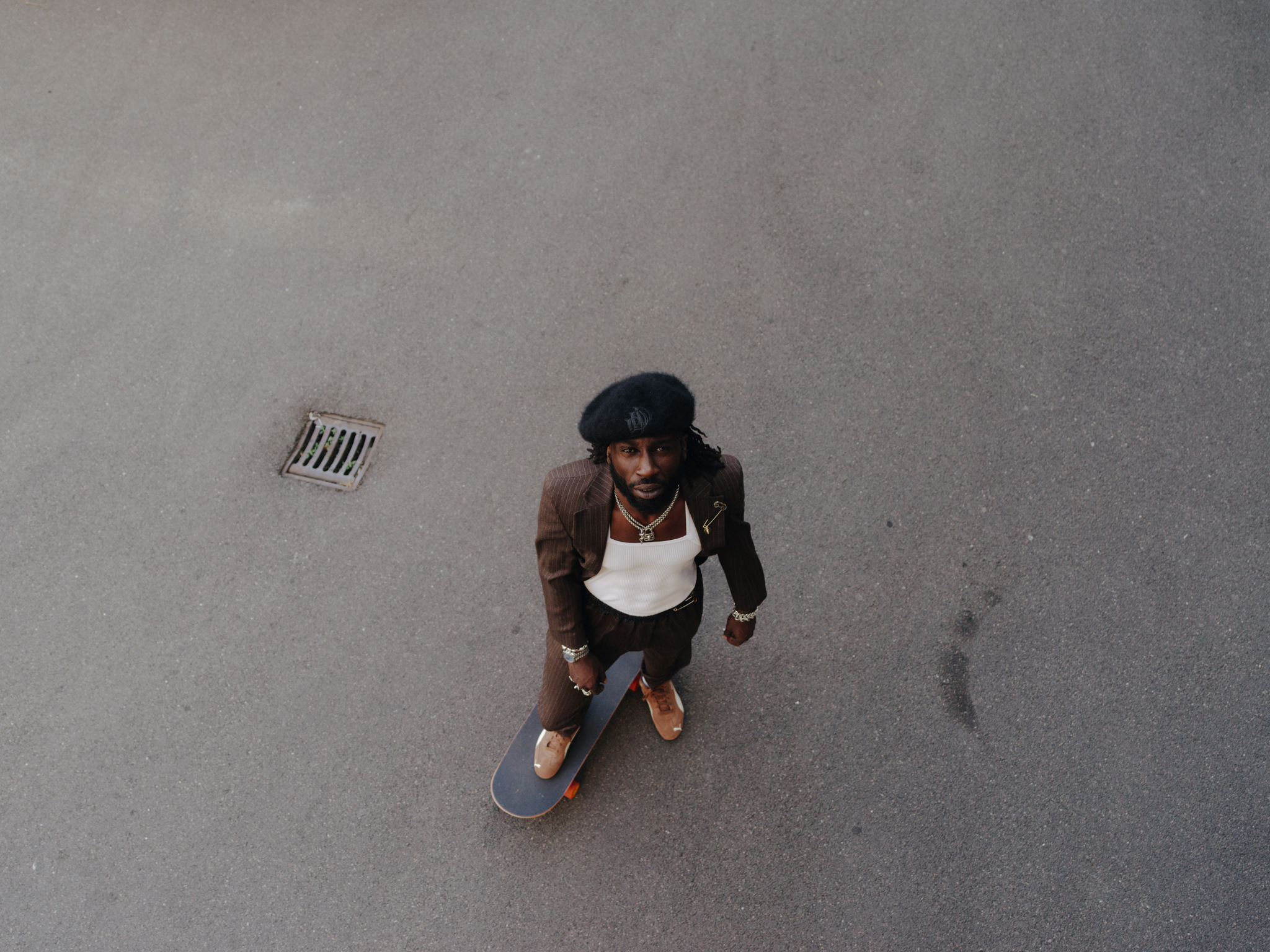 Overhead view of person in white apron and dark clothing holding mop on wet grey floor with scattered pink stains and white drain grate.