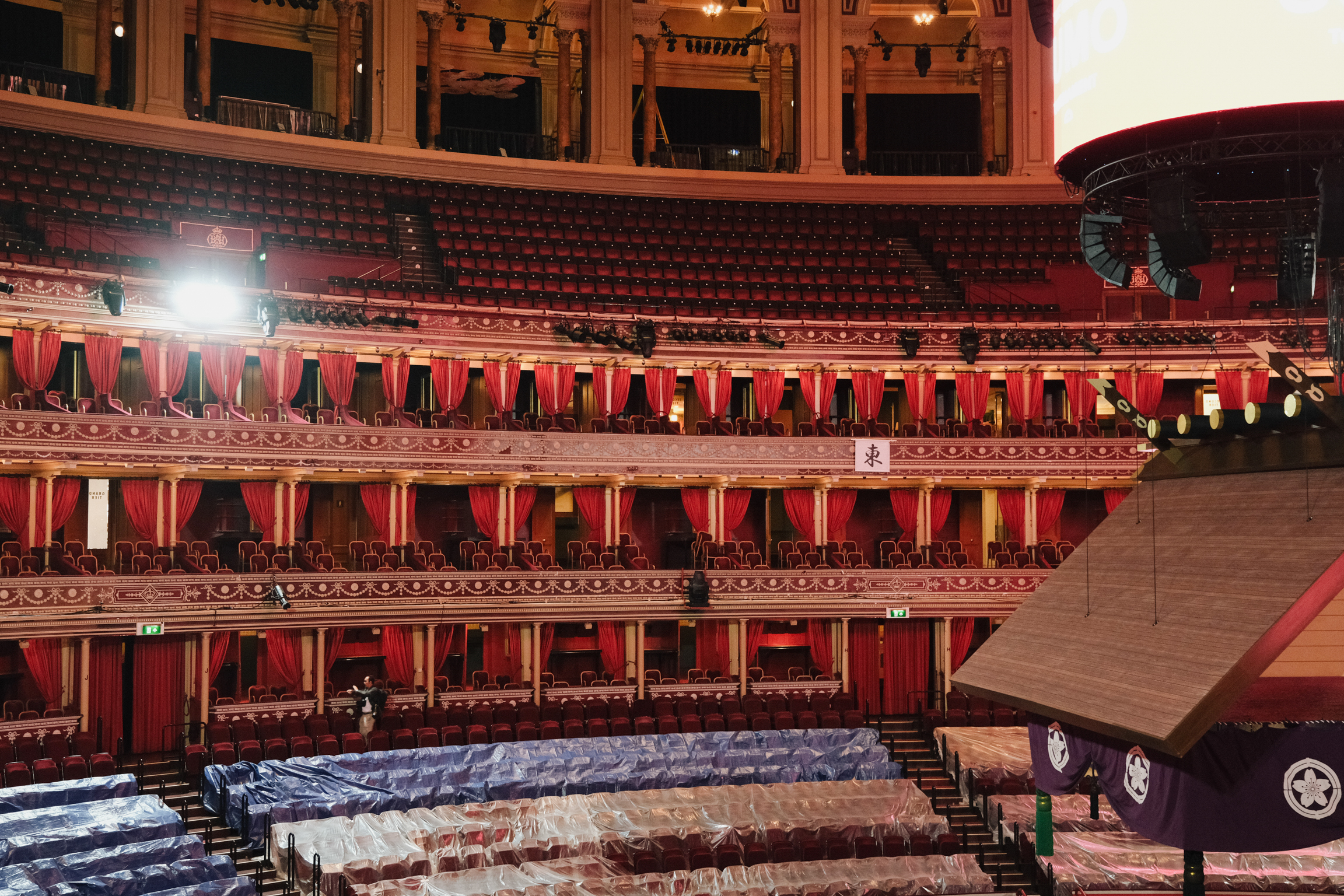 Interior of ornate theatre with red velvet seats, gold decorative details, multiple tiers of private boxes, and curved balconies.