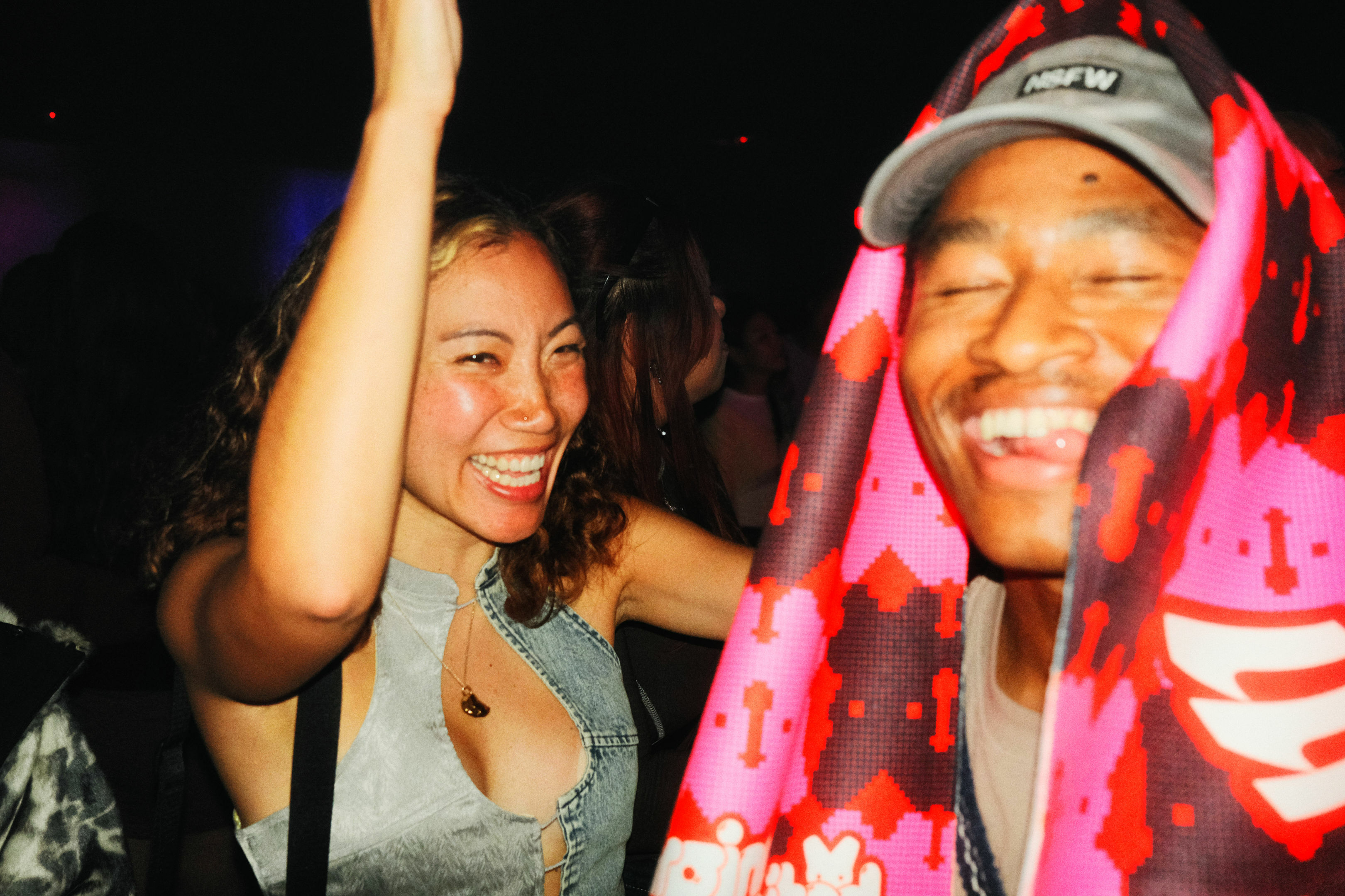 Smiling people enjoying a night out, one person wearing a red hat and jacket.