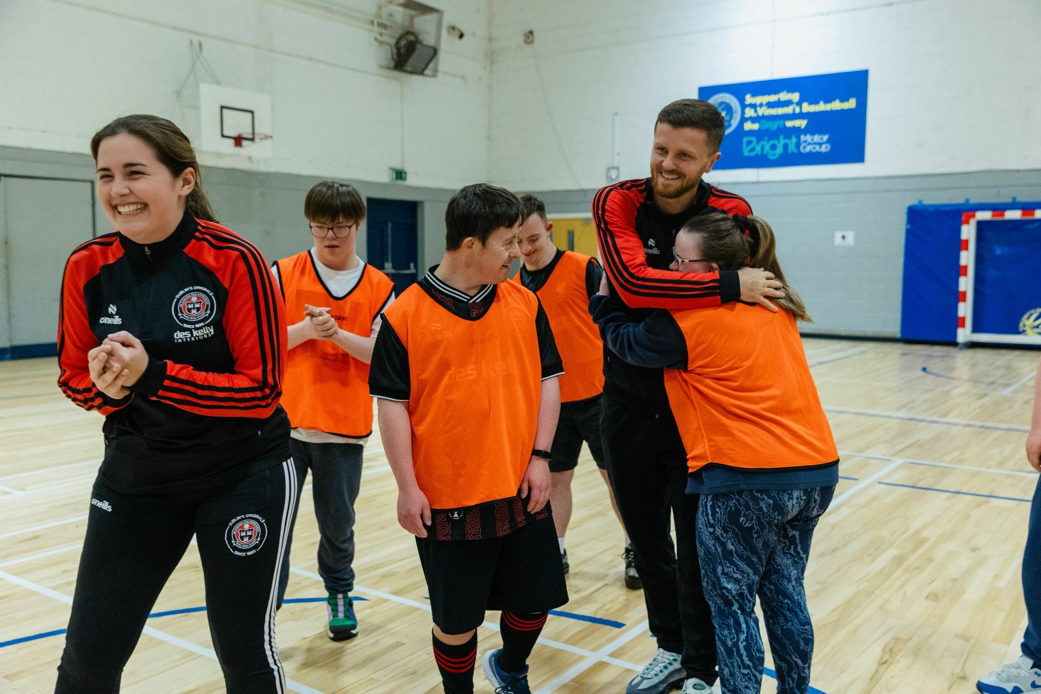 A group of young people in sports jerseys and shorts, playing together in a sports hall.
