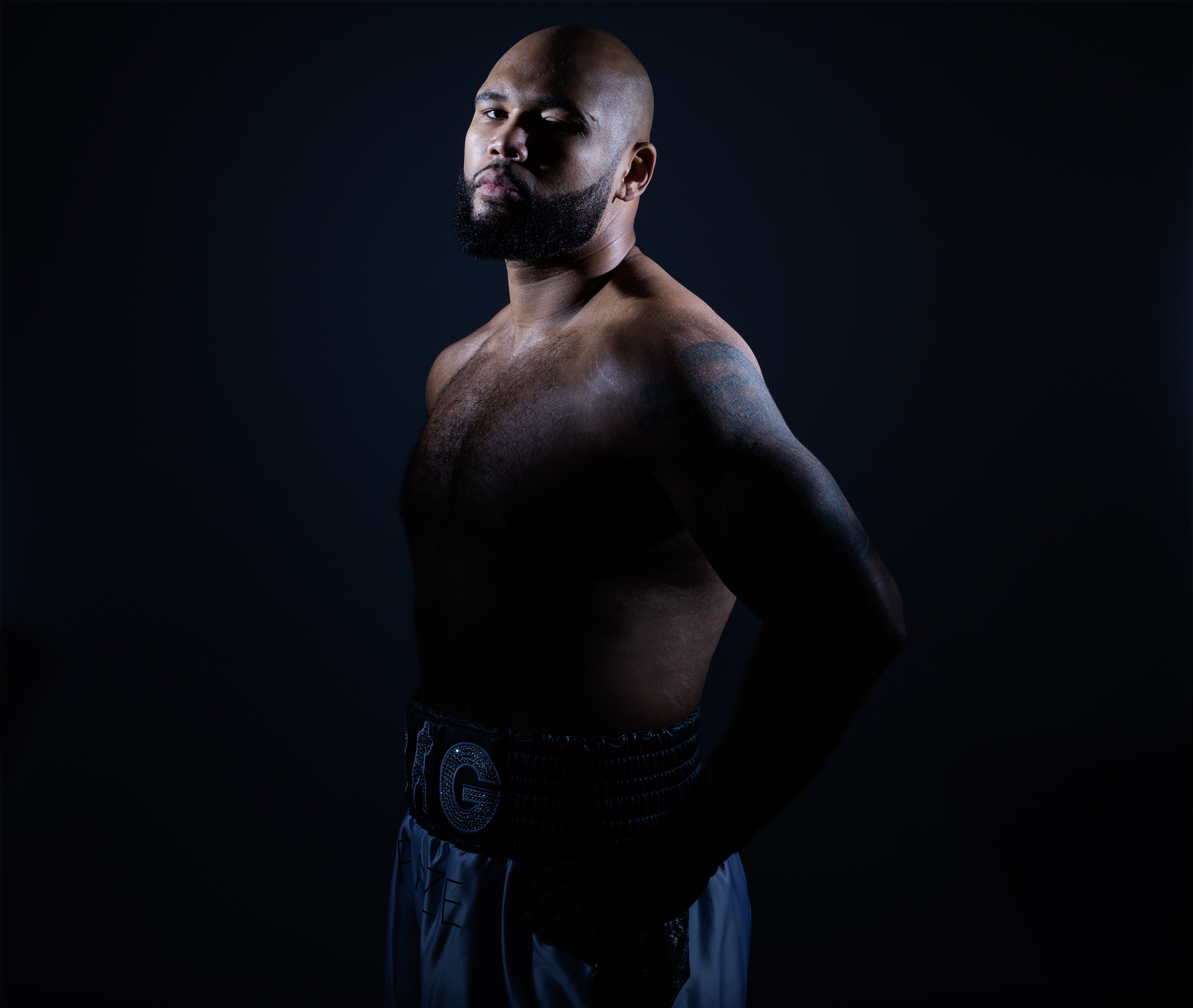 Shirtless male figure against a dark background.
