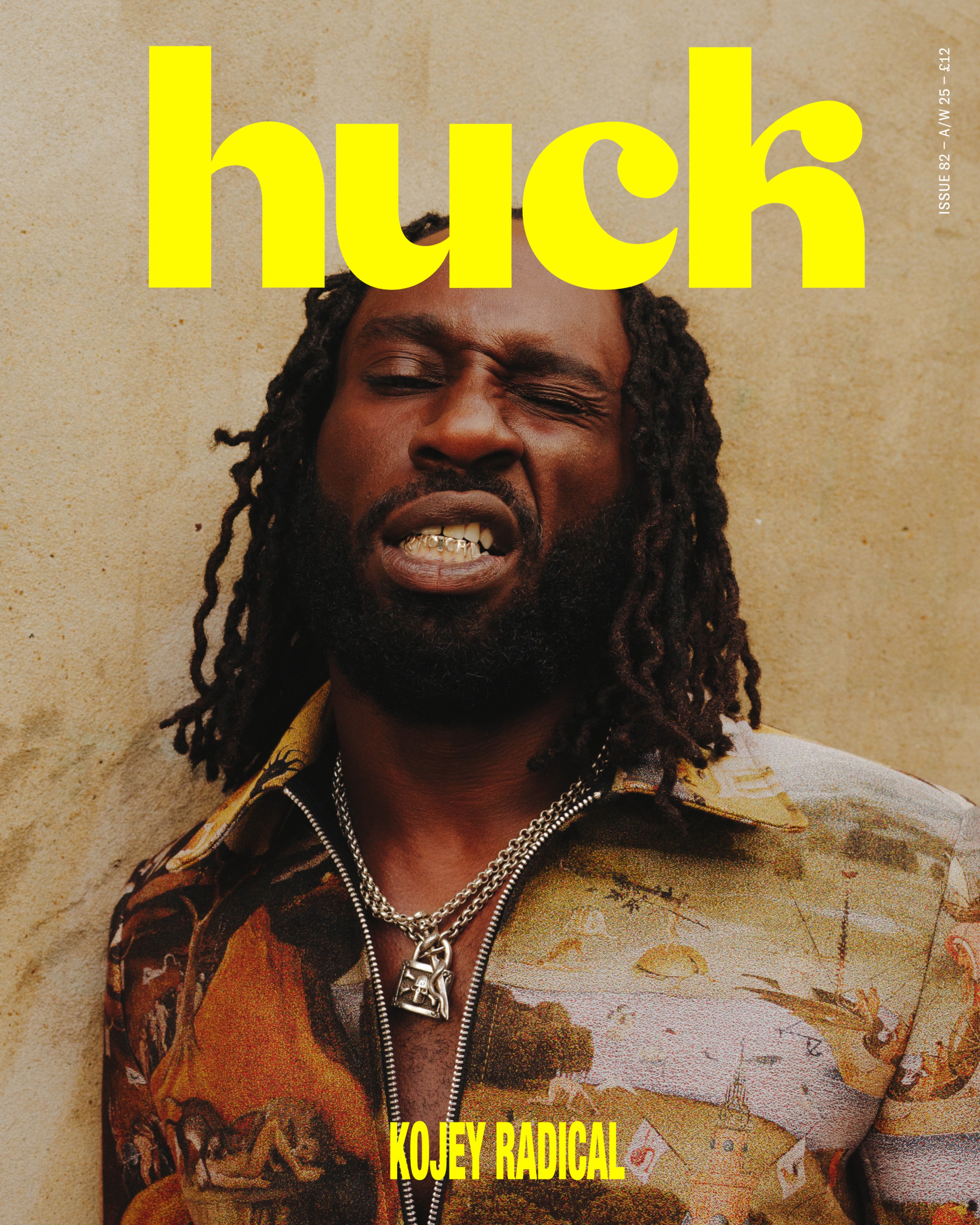 Magazine cover showing man with locs winking, wearing camo jacket and chains. Large yellow "huck" text at top, "KOJEY RADICAL" in yellow at bottom.