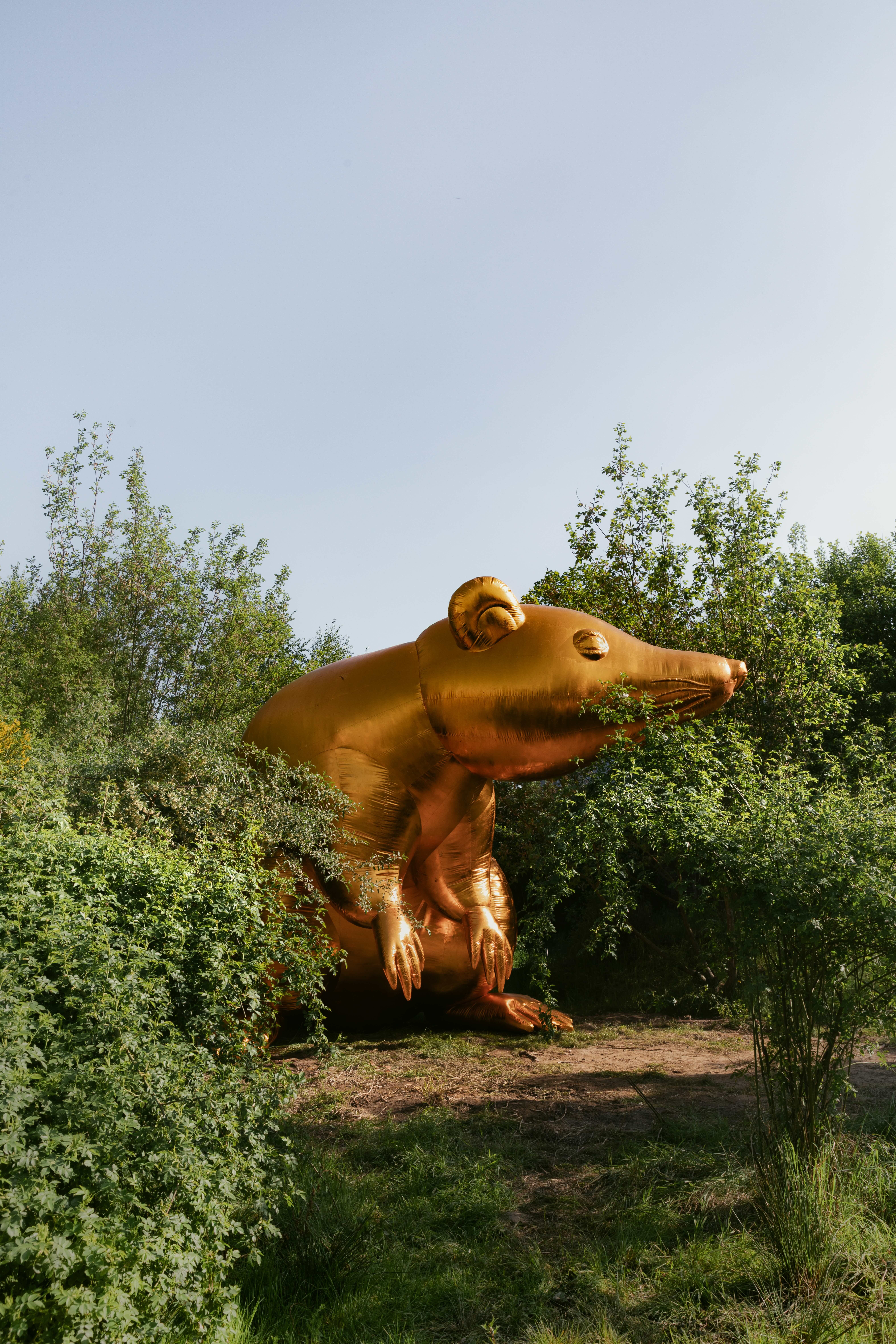 Giant gold statue of an animal figure in a wooded area.
