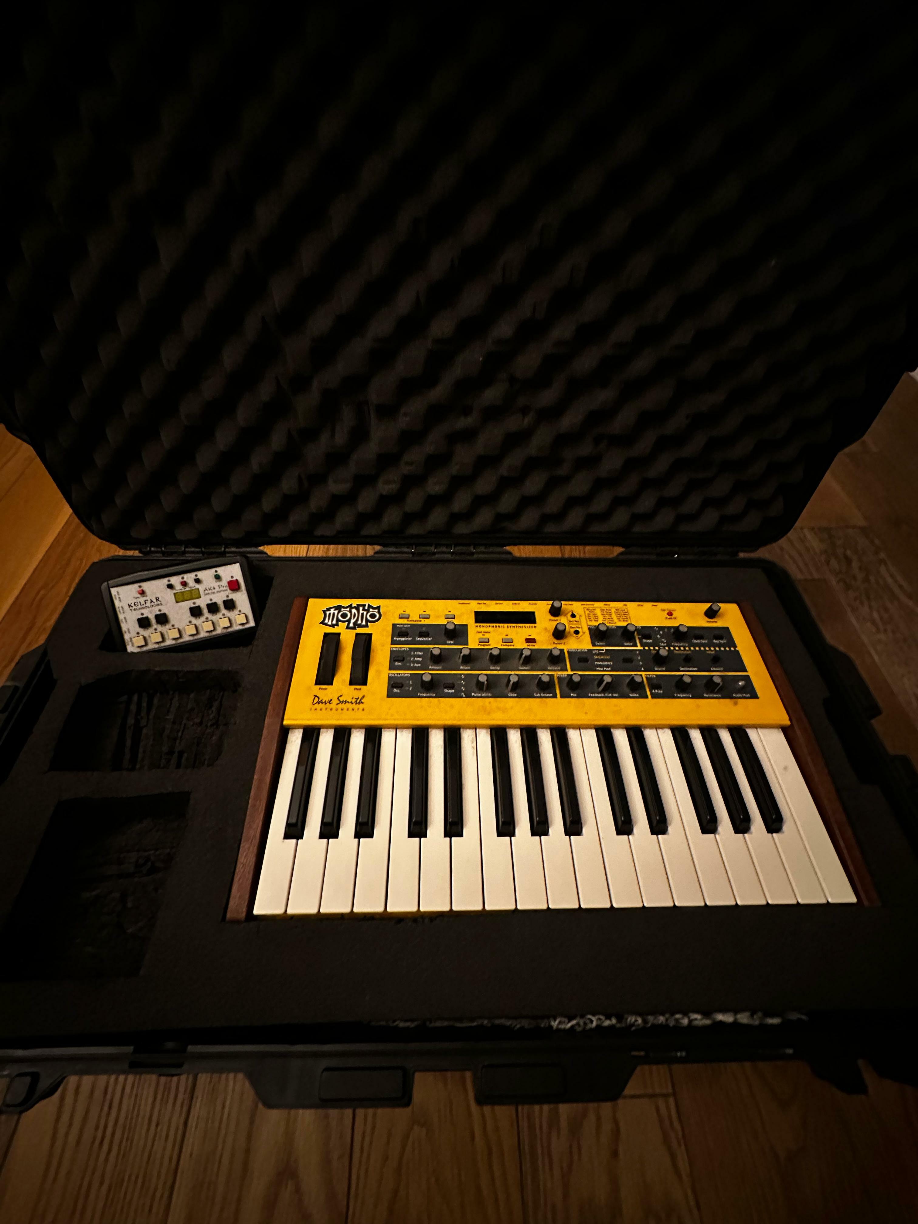Yellow electronic keyboard and synthesiser with controls on a dark background.
