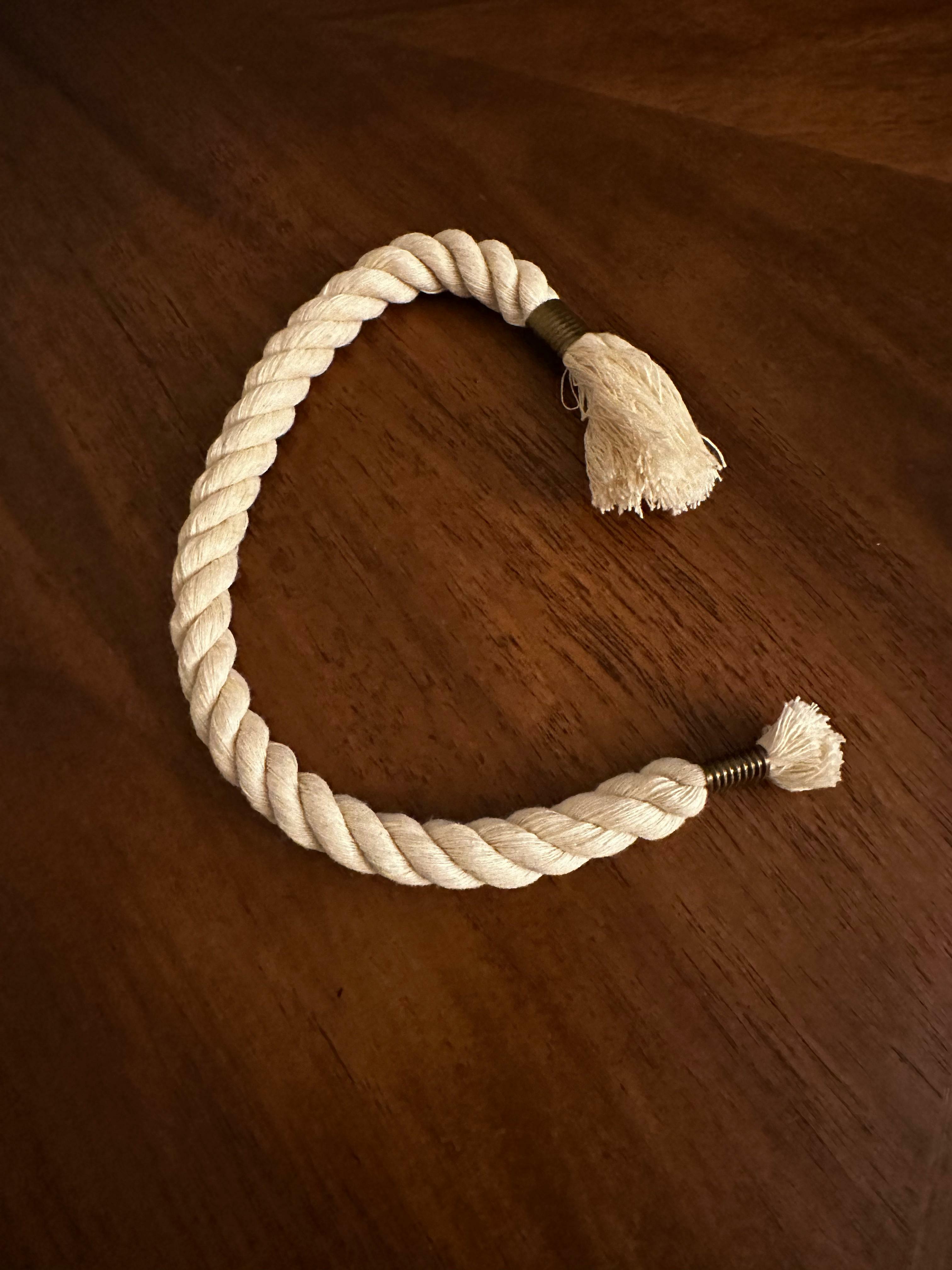 Plaited white rope in a heart shape on a wooden surface.