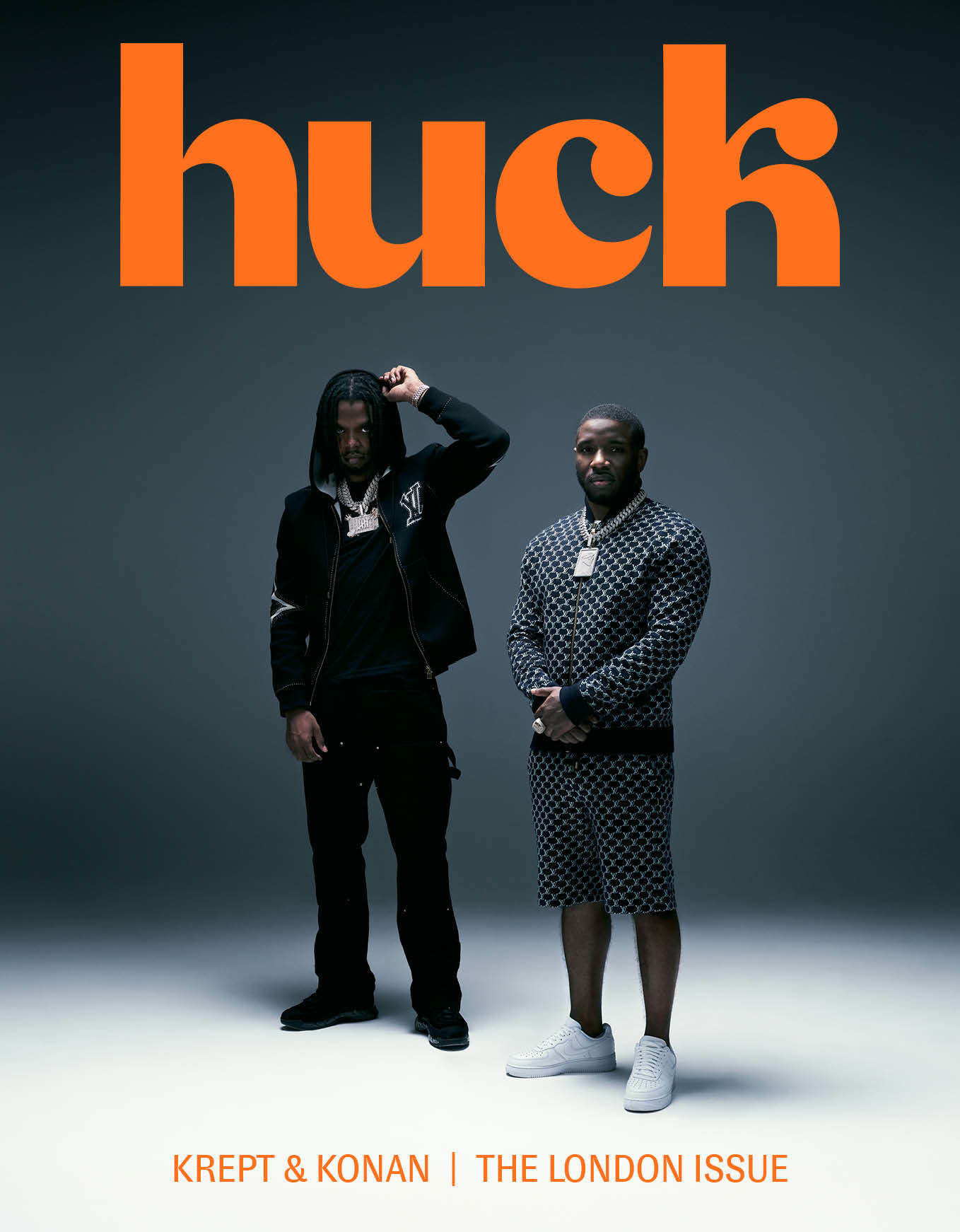 Two individuals standing against a dark background with large orange text 'huch' above them.