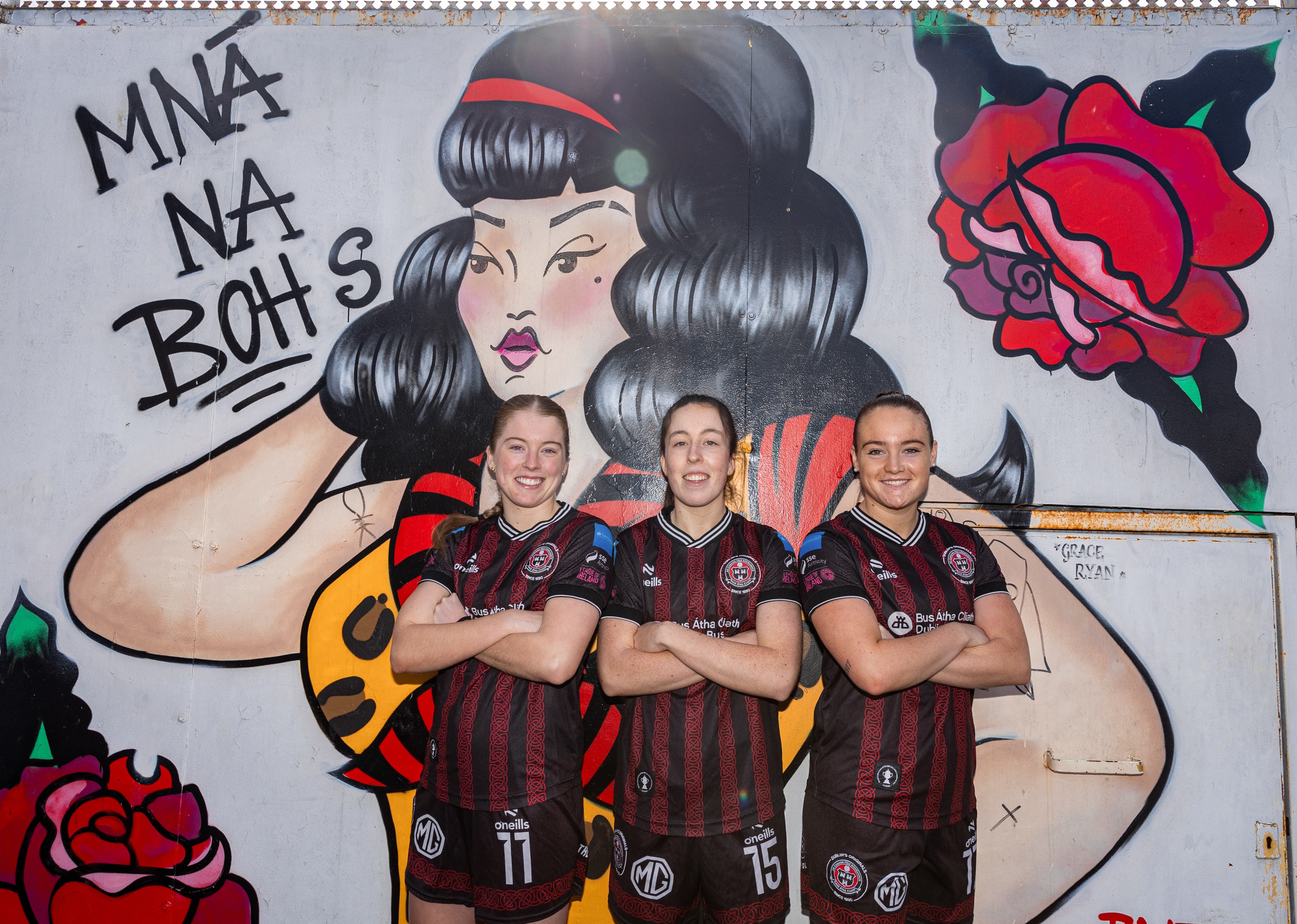 Colourful graffiti mural featuring comic-style female figure and three football players posing in front of it.