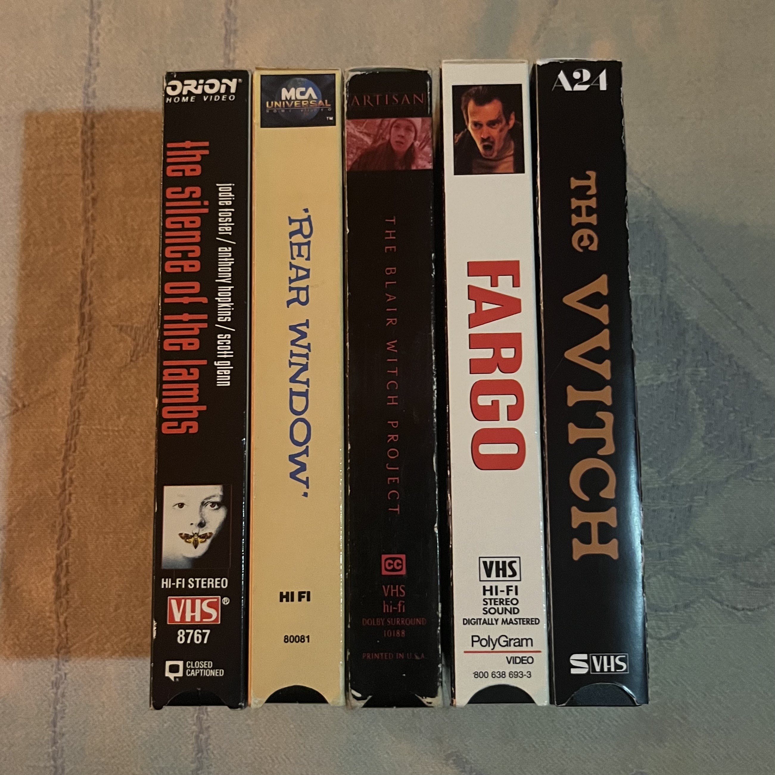 Five VHS video cassettes standing upright showing spines with titles including "Silence of the Lambs", "Fargo", and "Vvitch".