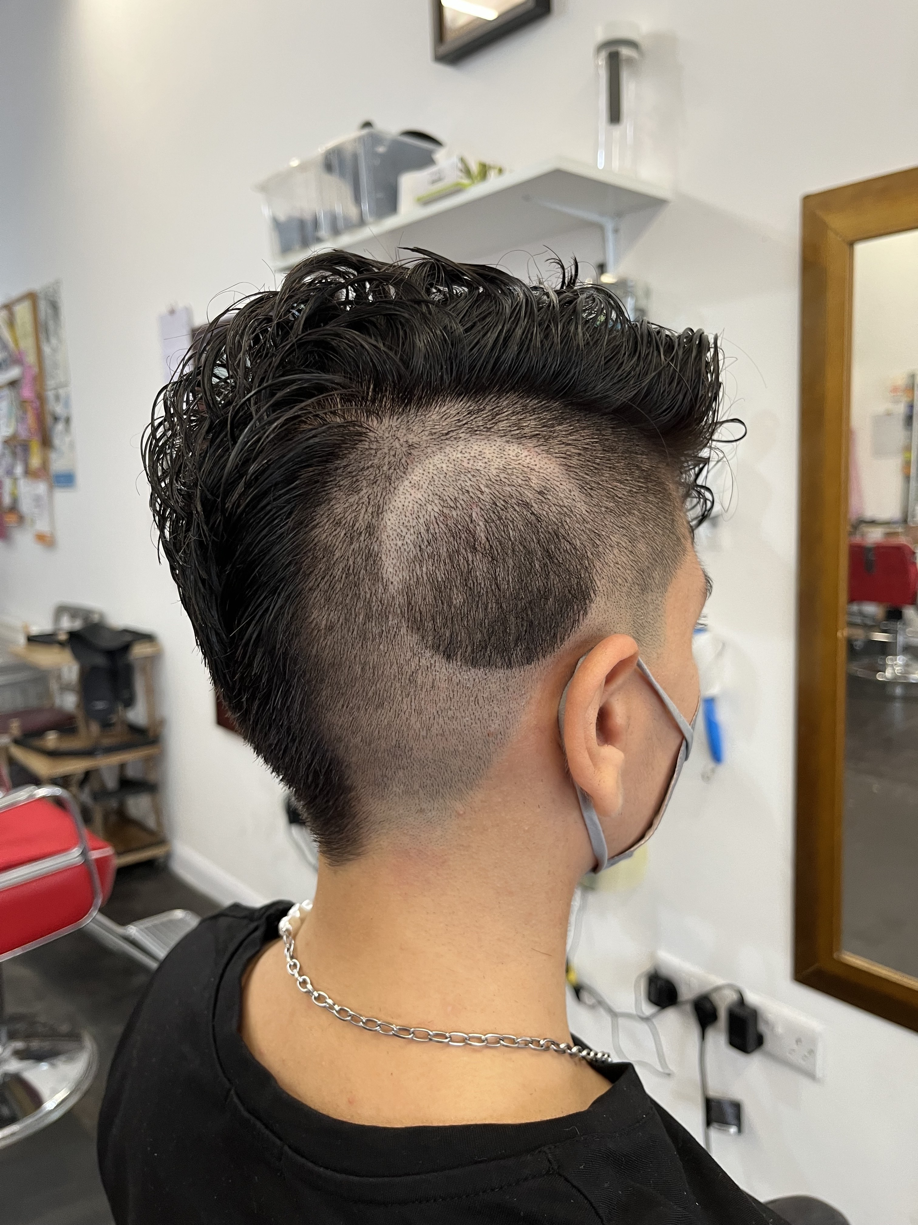 Back view of person with a curly hairstyle and undercut design.