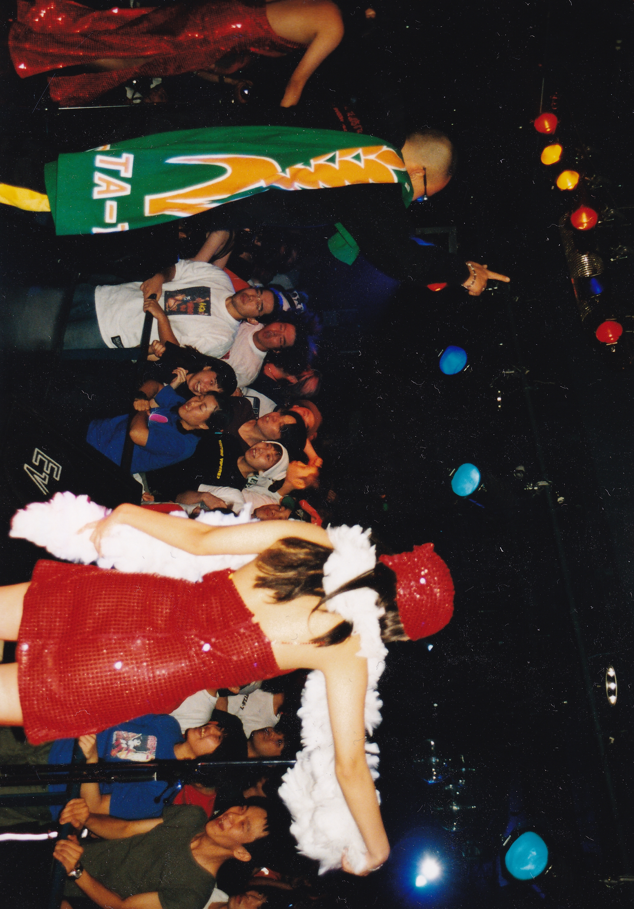 People in festive clothing at party with coloured balloons scattered on dark floor, image rotated 90 degrees anticlockwise.