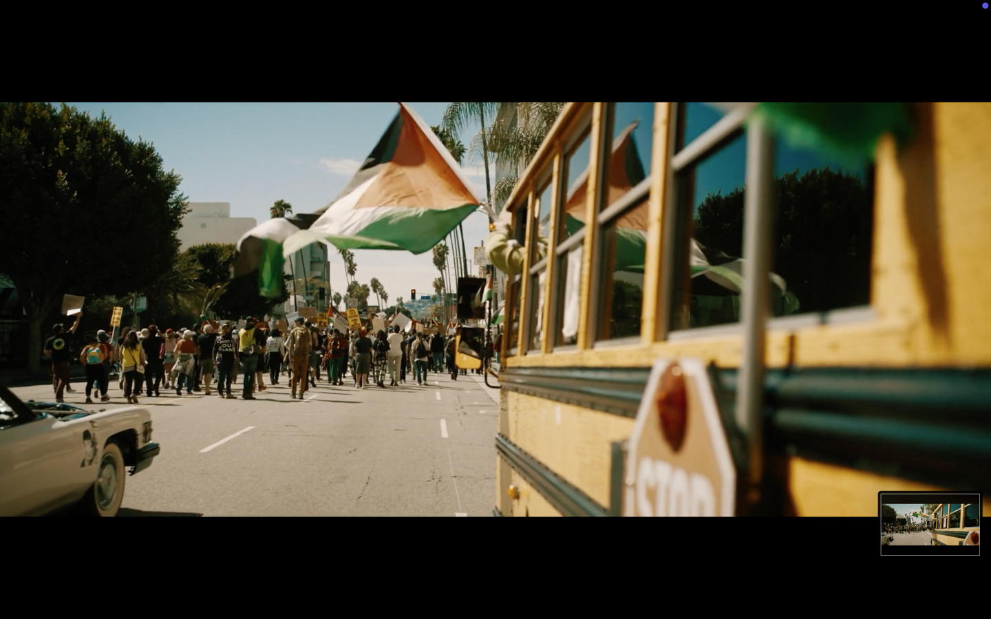 Crowd of people waving Indian flags on a street lined with buildings and vehicles.