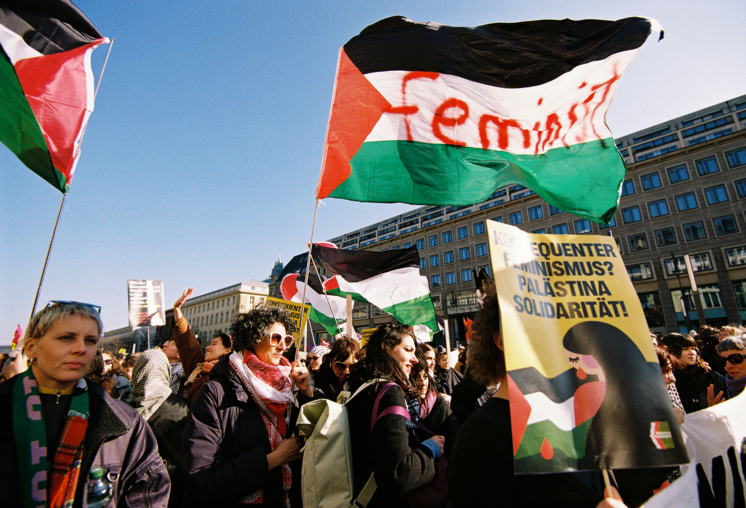 Crowd of people waving Palestinian flags and banners during a protest.