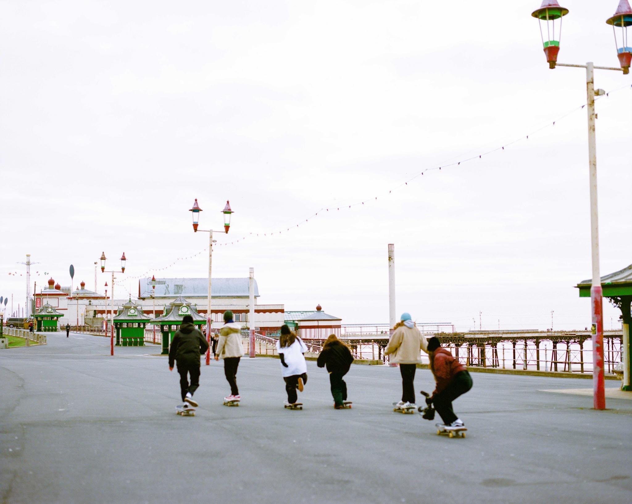 Colourful lanterns, people roller skating on a pier with buildings in the background.