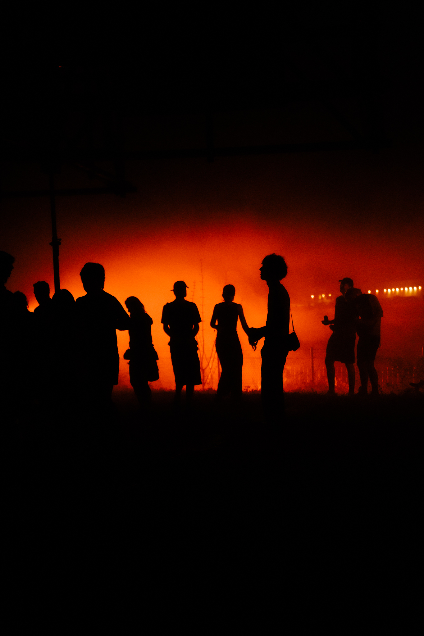 Silhouettes of people against a fiery orange sky.