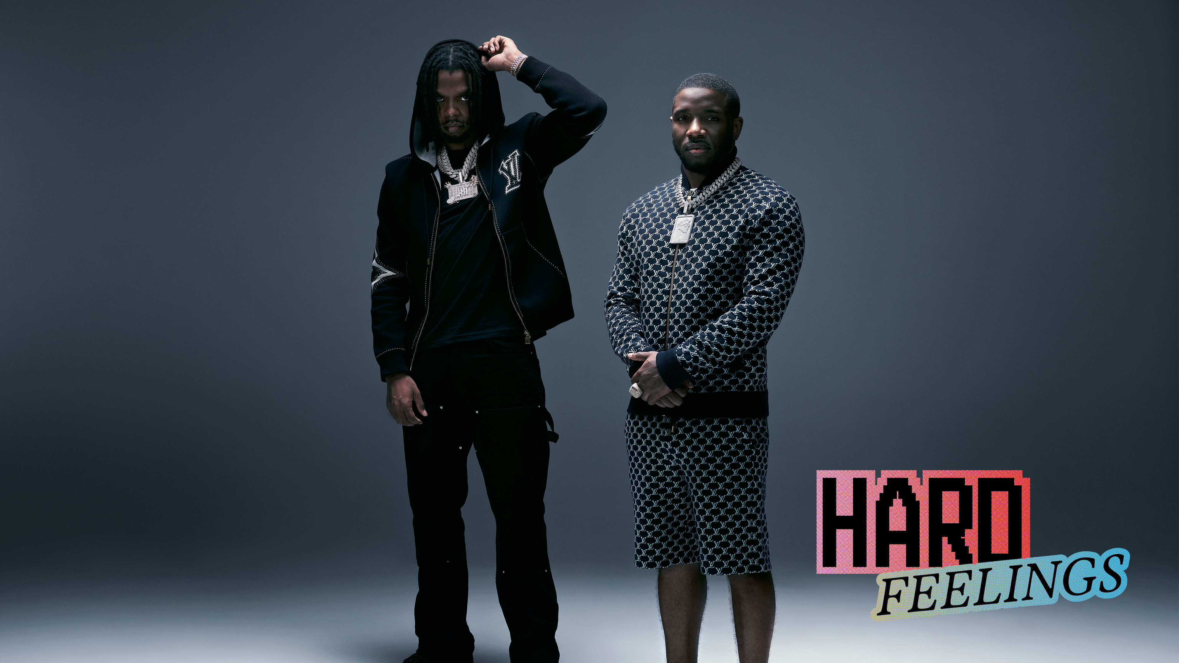 Two men in dark clothing against grey background. Left wears black hoodie, right in patterned robe. Pink "HARD" text with "FEELINGS" below in bottom right corner.