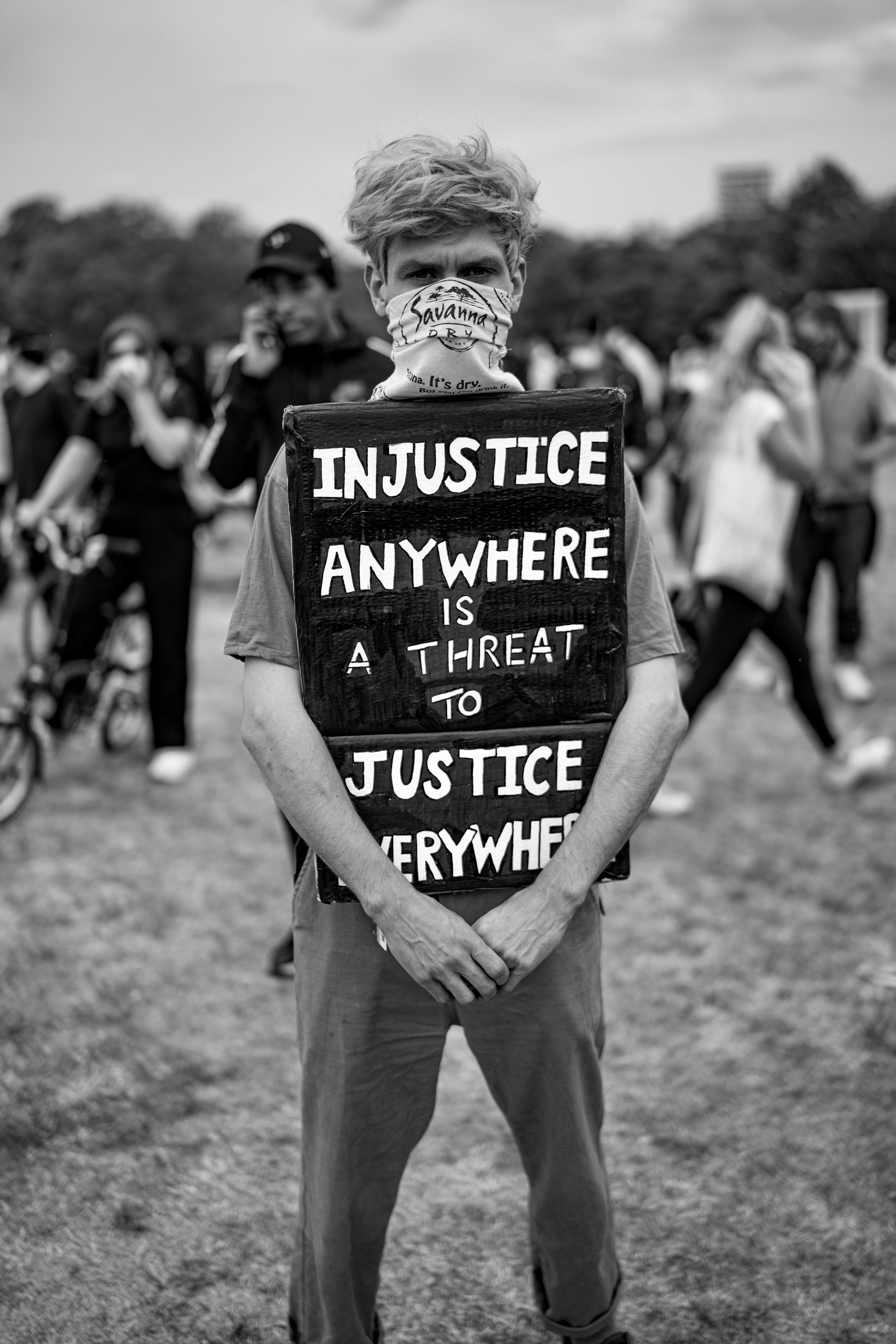 Person holding sign saying "Injustice anywhere is a threat to justice everywhere" at a protest.