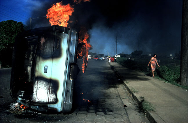 Overturned vehicle on fire, with thick smoke and flames on a dark country road.