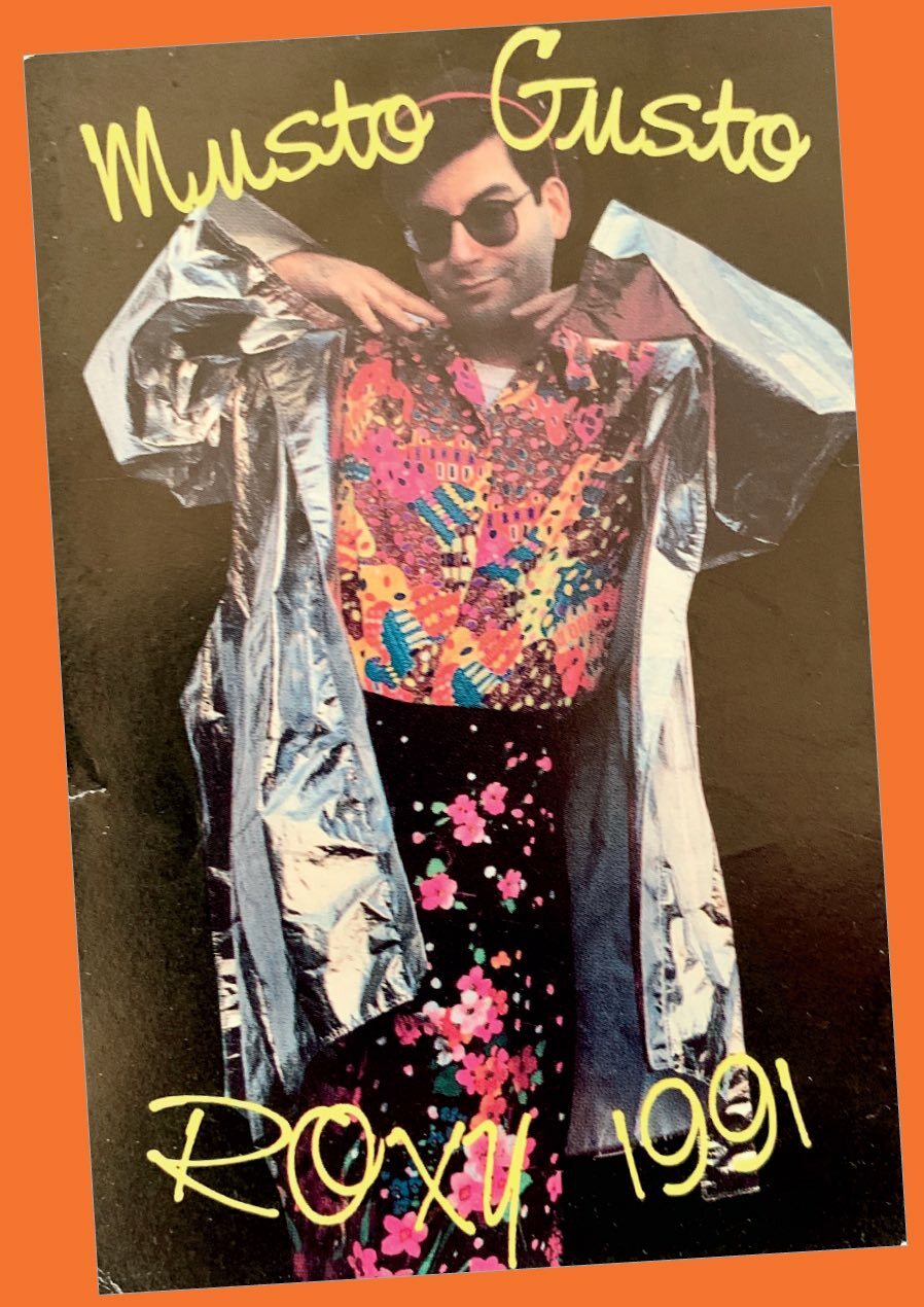 Man in floral and metallic outfit with sunglasses, posing against orange background with text "Muusto Gussto Roxy 1991".