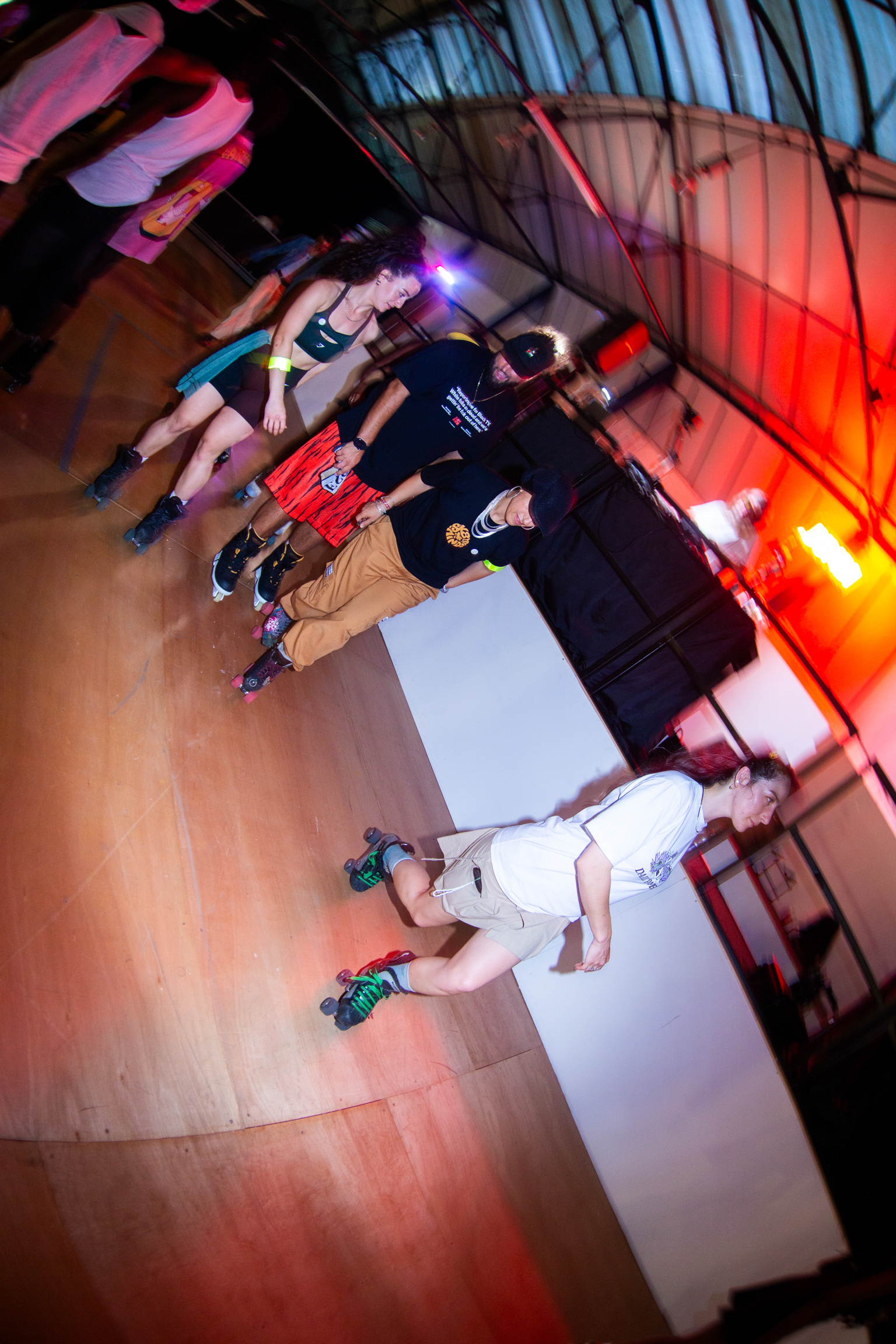Person roller skating at indoor rink with coloured lighting, viewed from above at rotated angle.