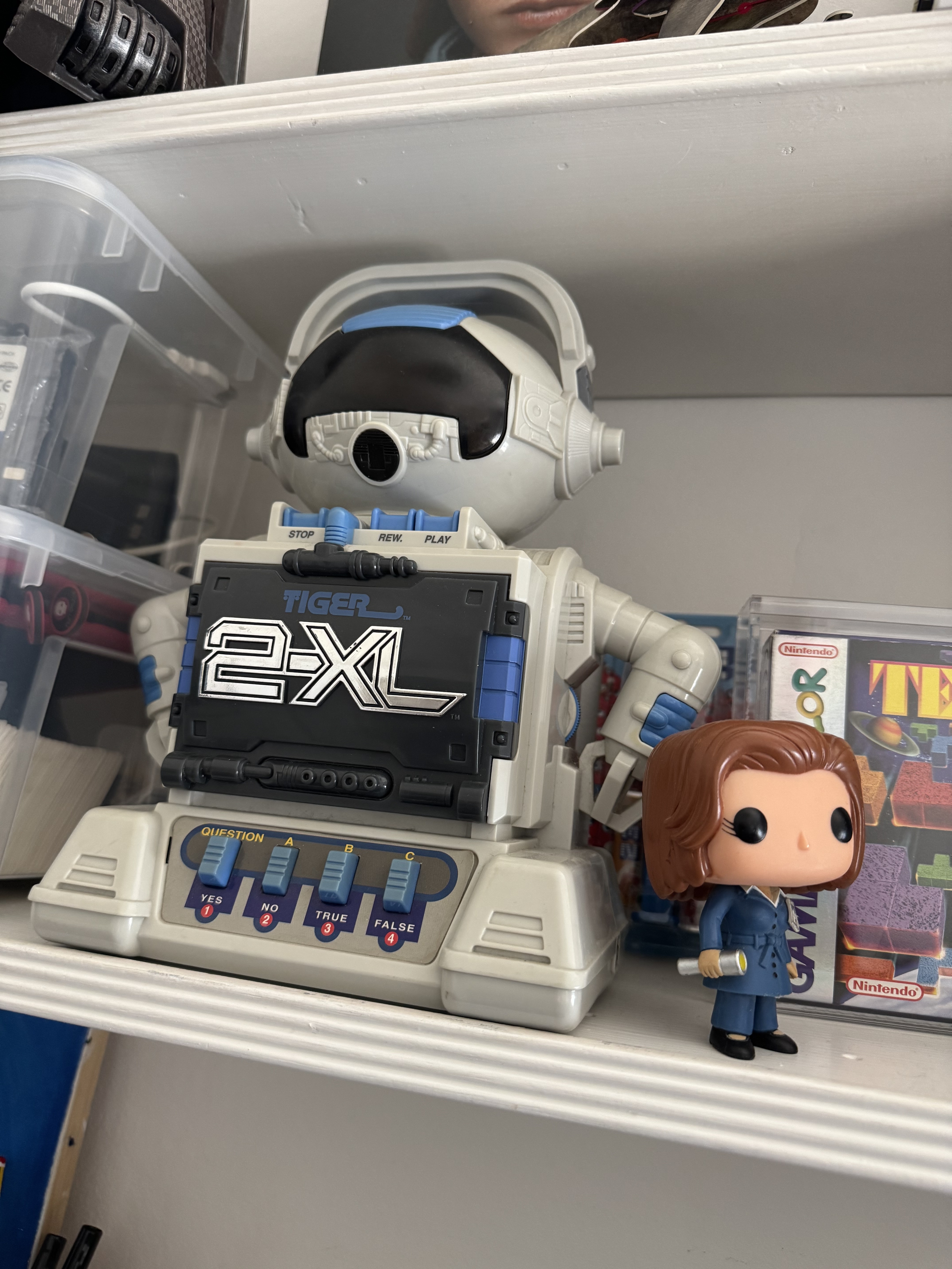 Shelves filled with electronic toys and figurines, including a 2XL robot and a Funko Pop figure.