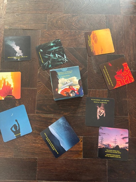 Various colourful book covers scattered on dark wooden parquet flooring, including orange, blue, red, and purple spines and covers.