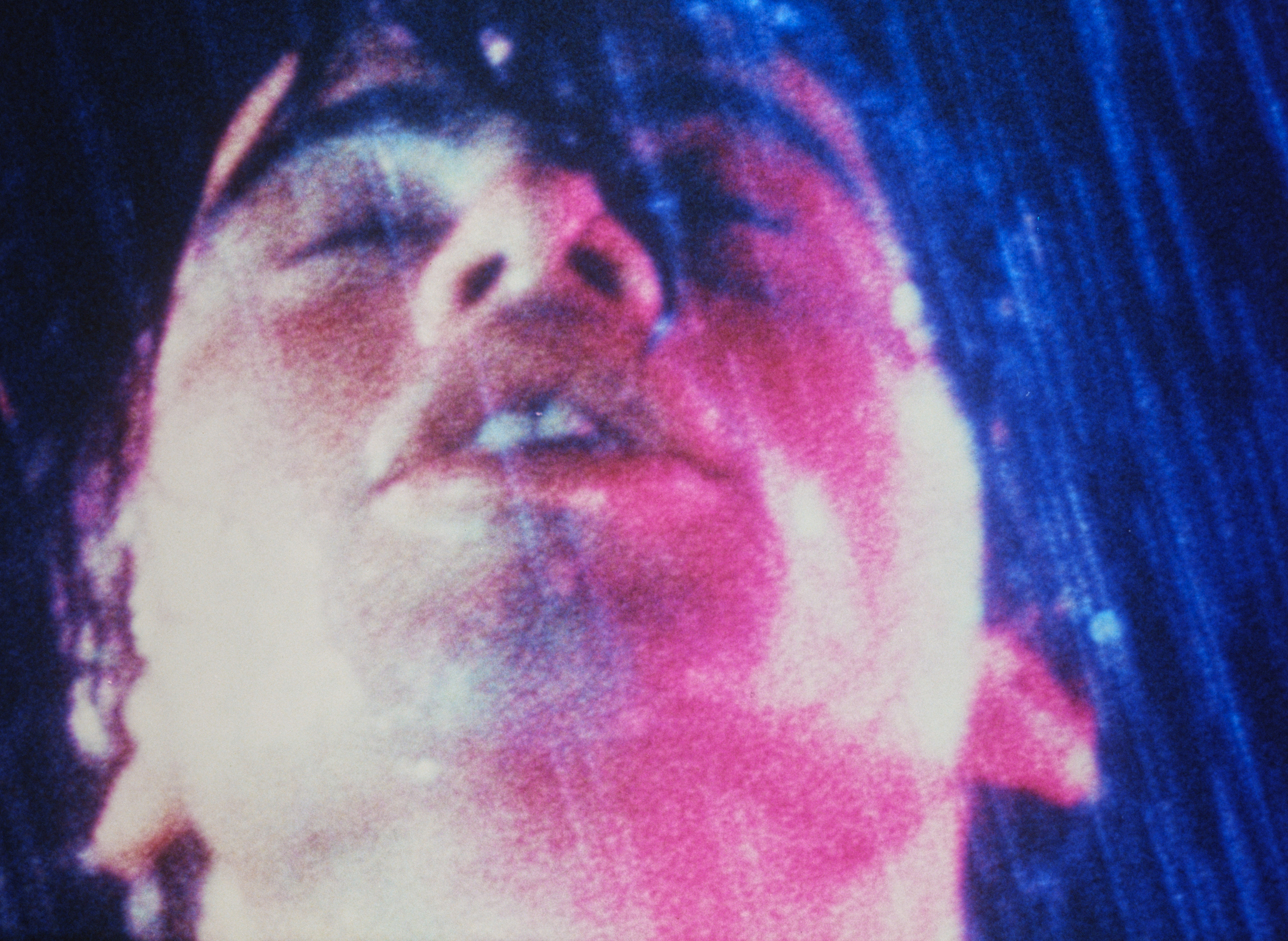 Closeup of person's face obscured in blue and pink lights.