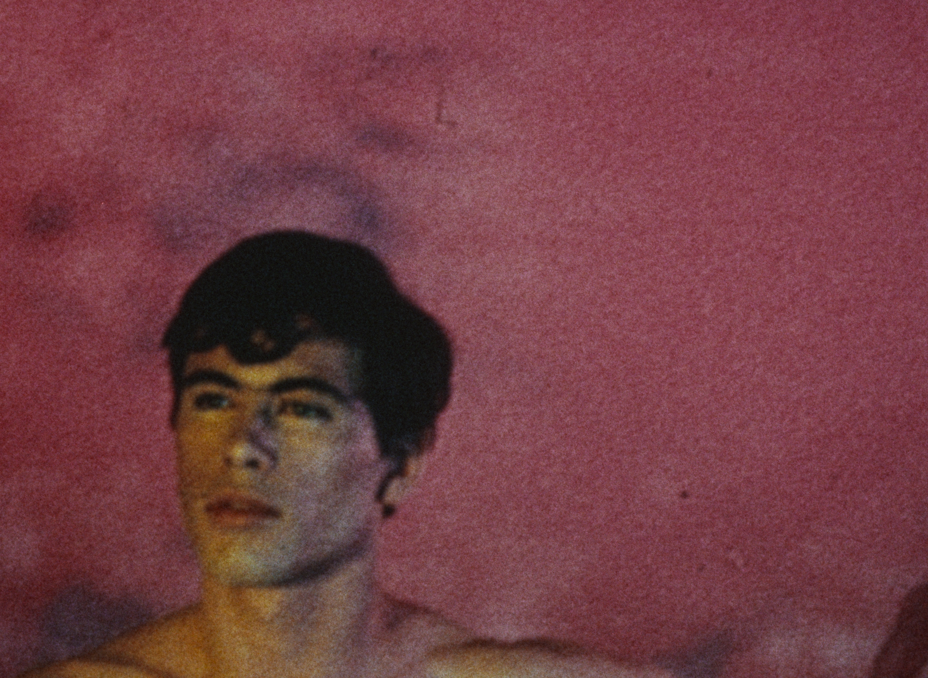 Headshot of a man with dark hair against a red background.