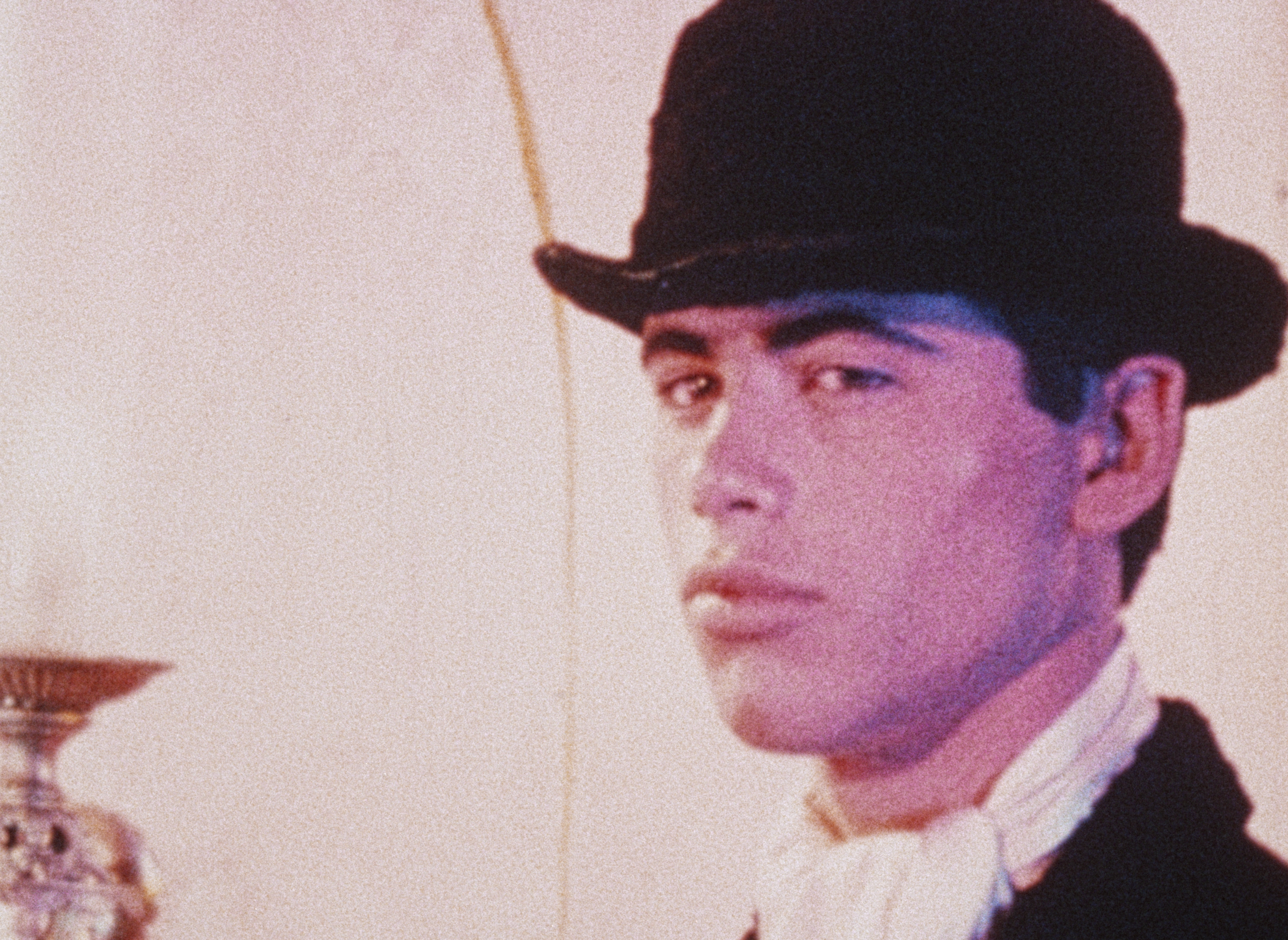 A man wearing a black hat, looking off to the side with a serious expression.