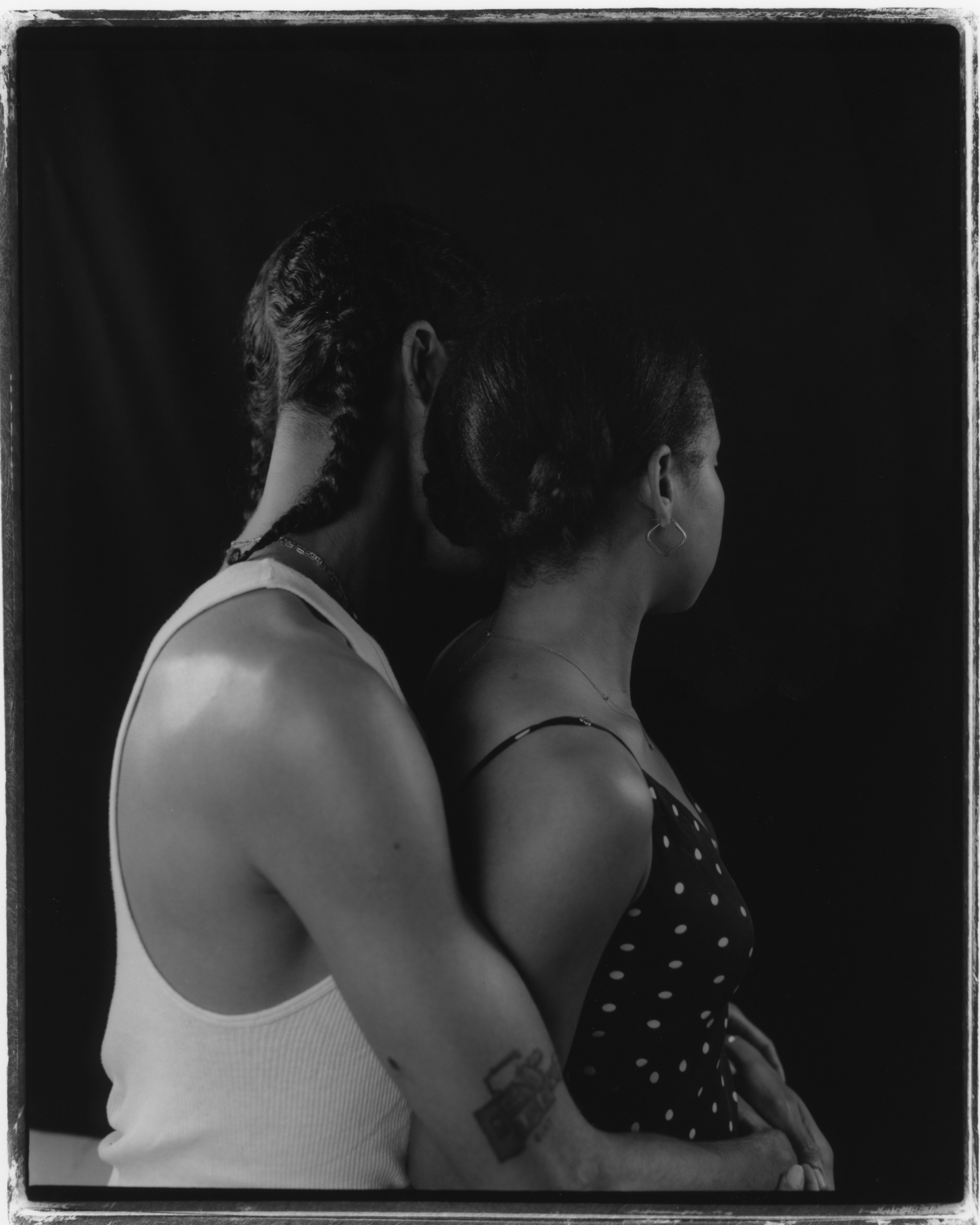 Black and white image of two people in an intimate embrace, with one person's face visible from the side.