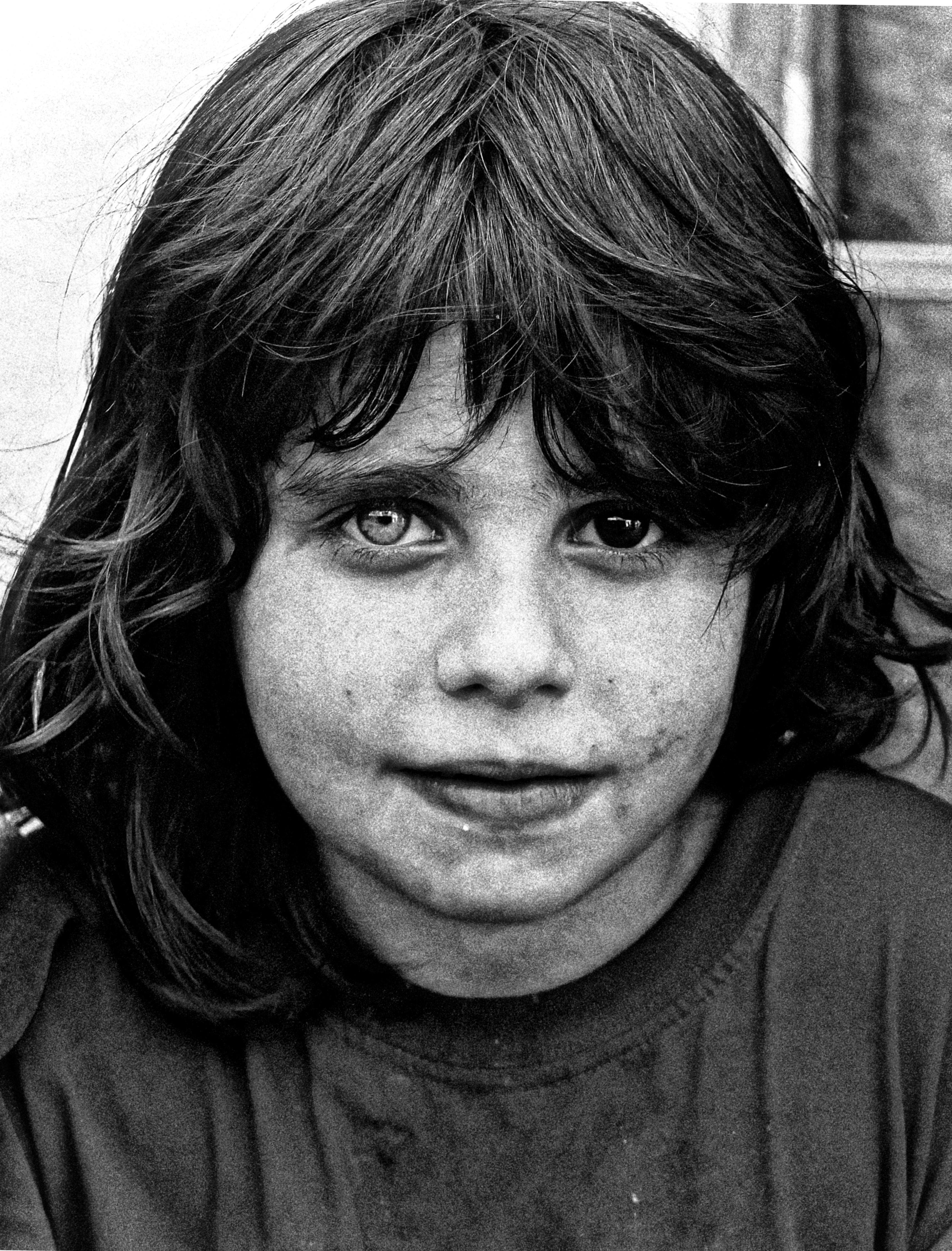 Close-up black and white portrait of a young girl with dark, wavy hair and piercing eyes.