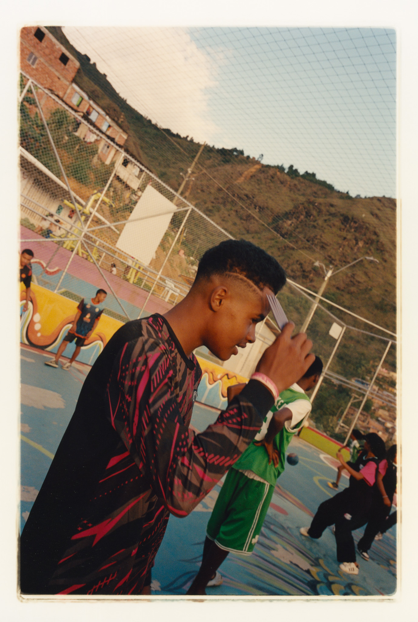 Colourful buildings and people in traditional African dress against a mountainous backdrop.