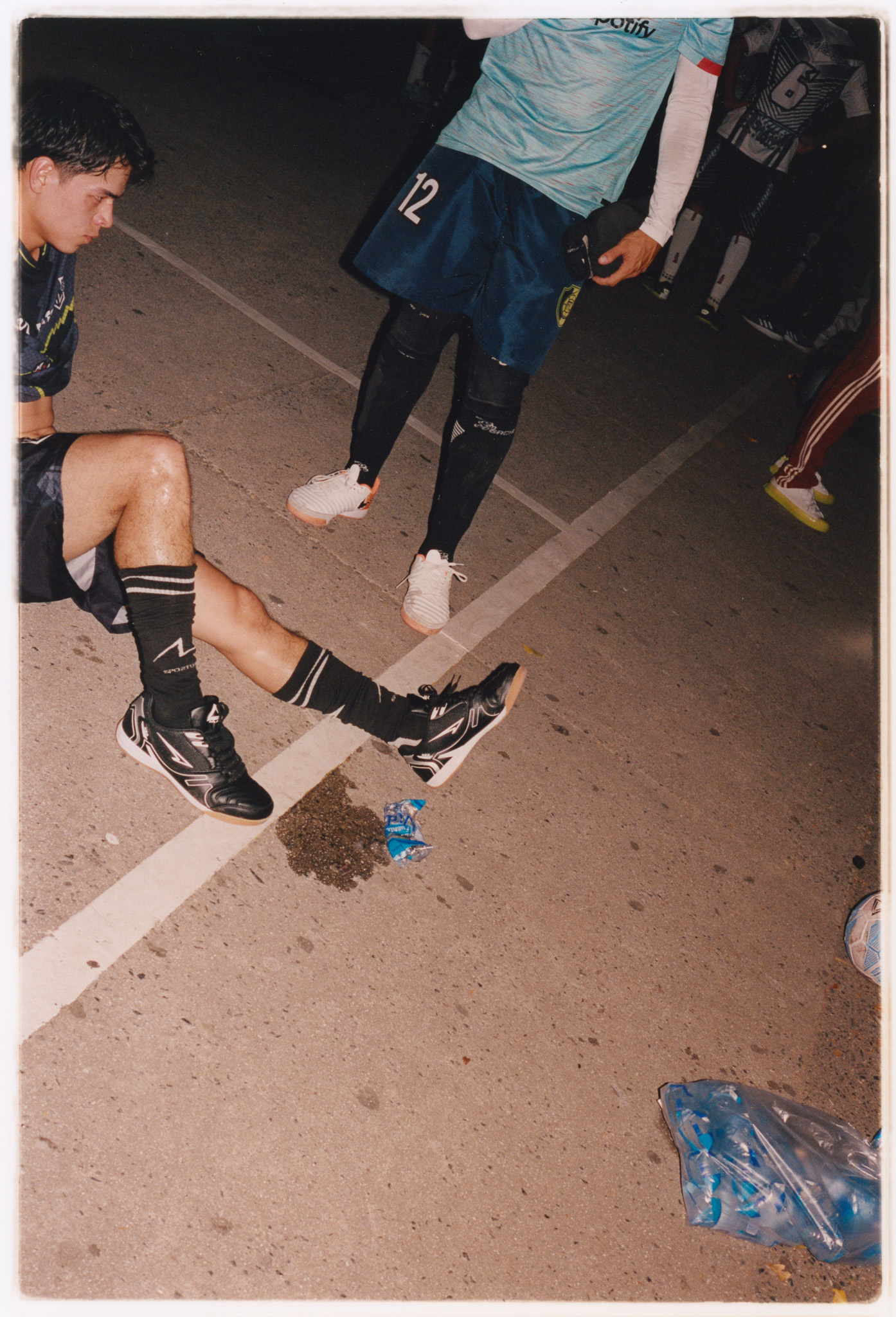 Crumpled plastic bags, players' feet on concrete floor, sports clothing.
