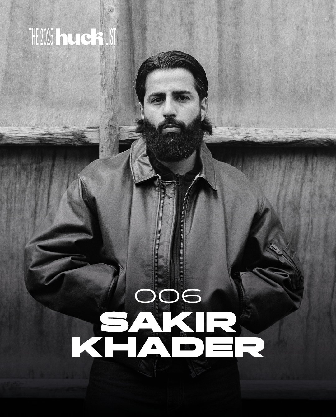 Headshot of a bearded man in a leather jacket standing in front of a wooden wall with the text "The 2005 huckster" and "006 SAKIR KHADER".
