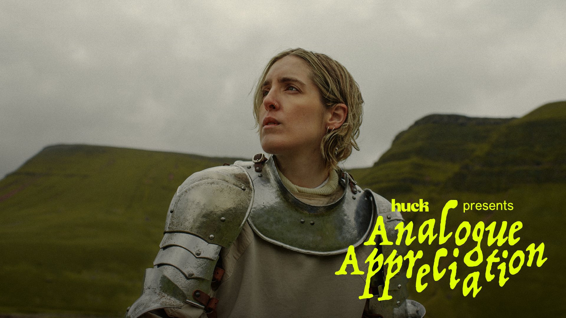 A person in a grey jacket stands against a mountainous, foggy landscape. The image has the text "huck presents Analogue Application" overlaid in yellow and green.