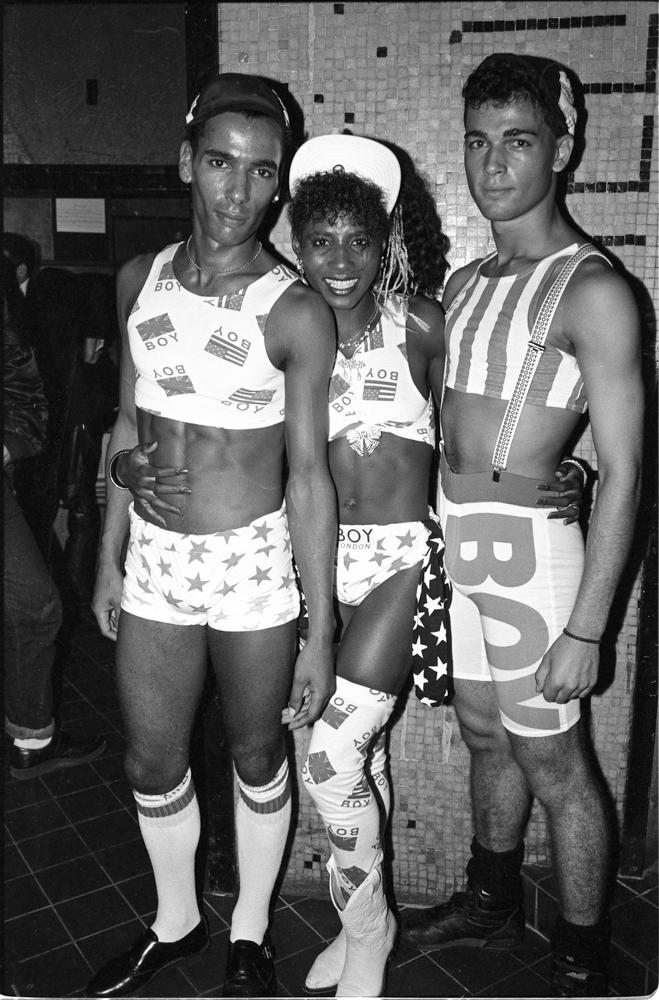 Three people in matching striped and star-patterned athletic wear posing together in black and white photograph from the 1980s.