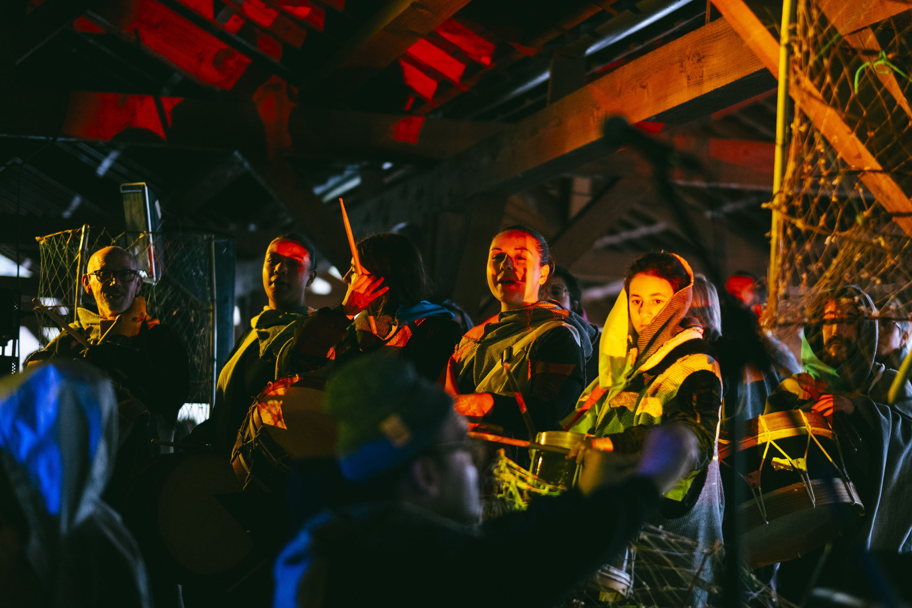 Crowd of people wearing bright jackets and headlamps, gathering in a dimly lit outdoor setting.