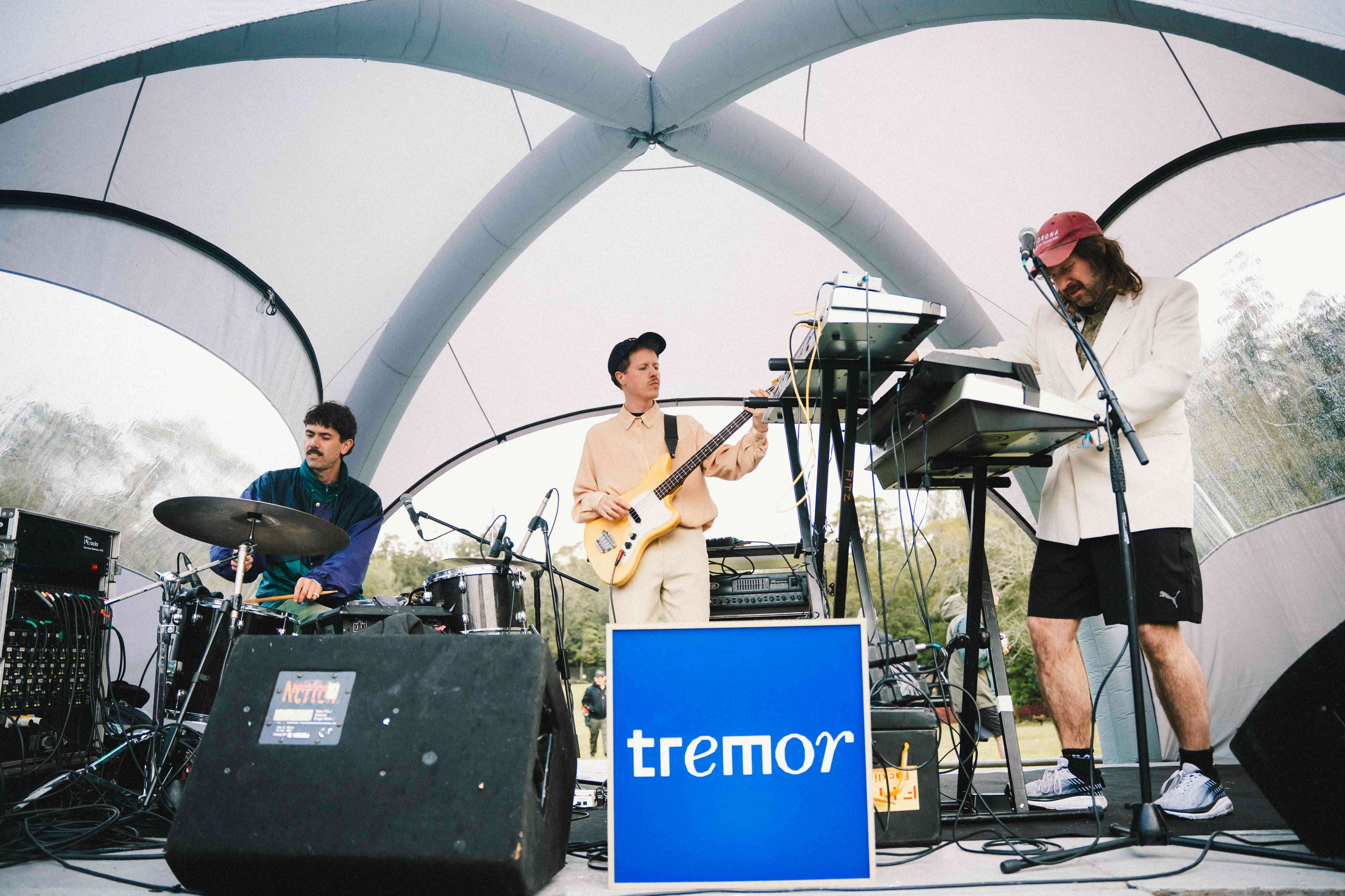 Three musicians performing on stage, playing musical instruments and using audio equipment. Stage is enclosed by a large inflatable dome structure.