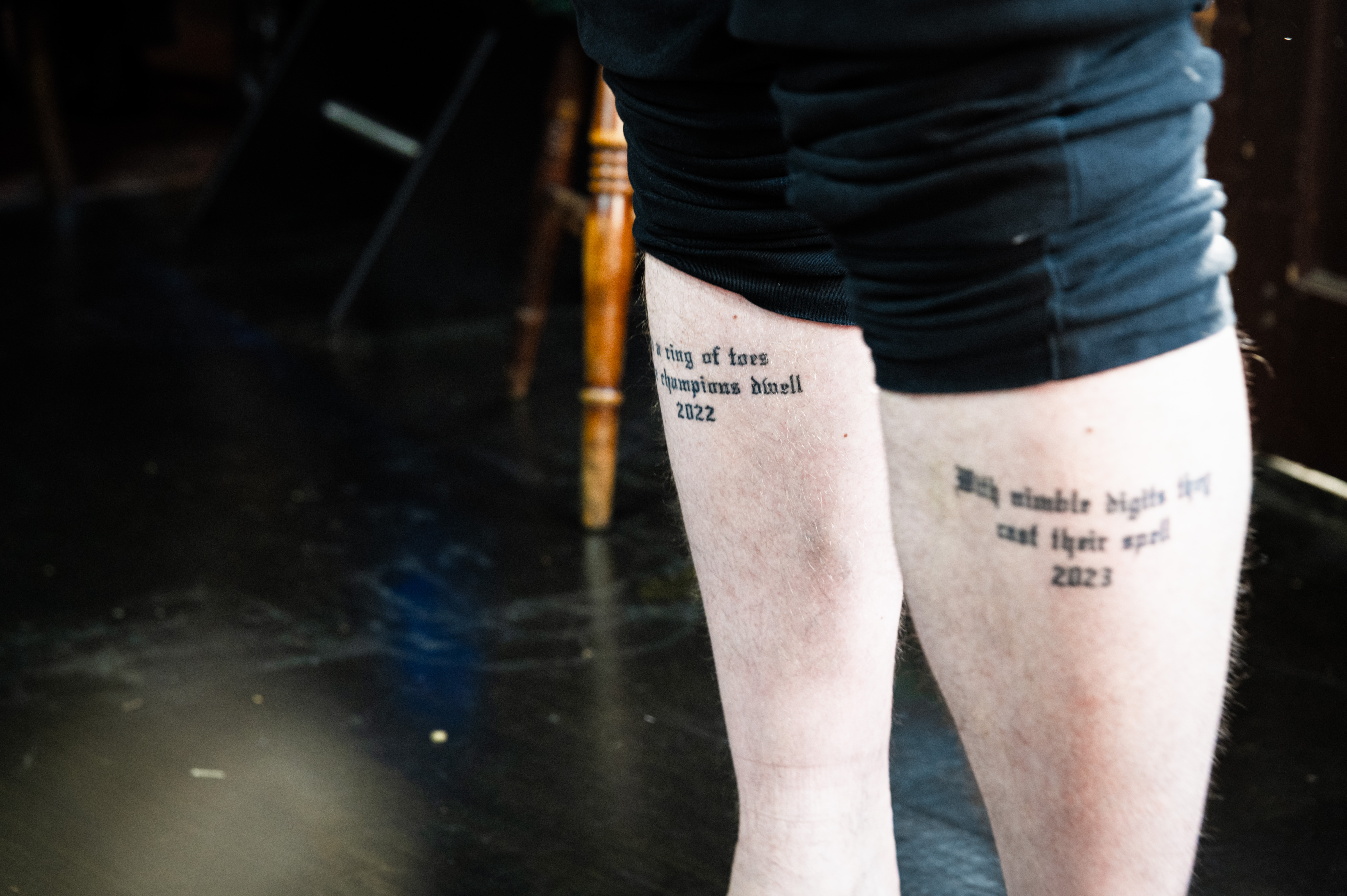 Tattoo on a person's legs, displaying text and imagery.