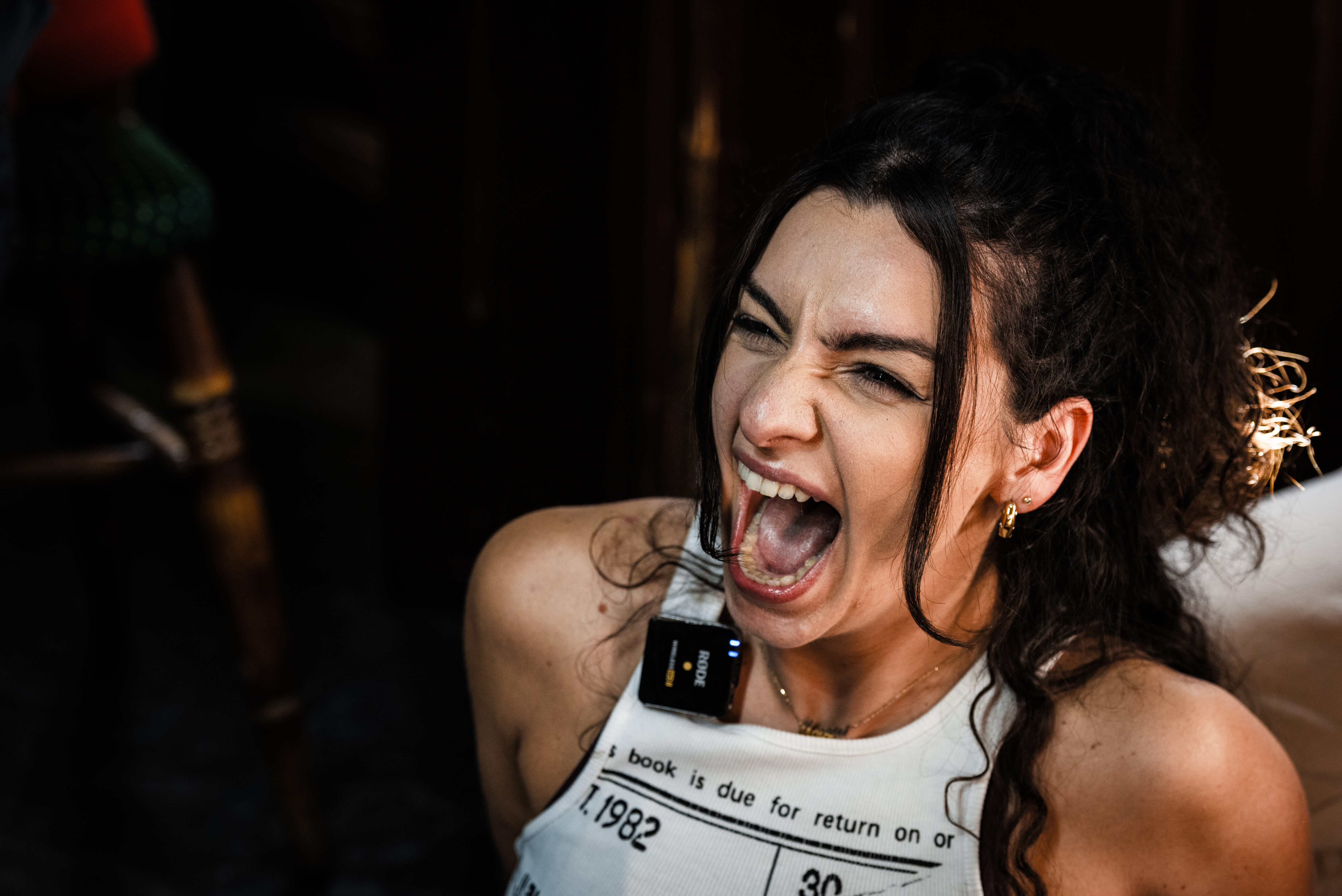 Woman shouting in workout gear, intense facial expression.