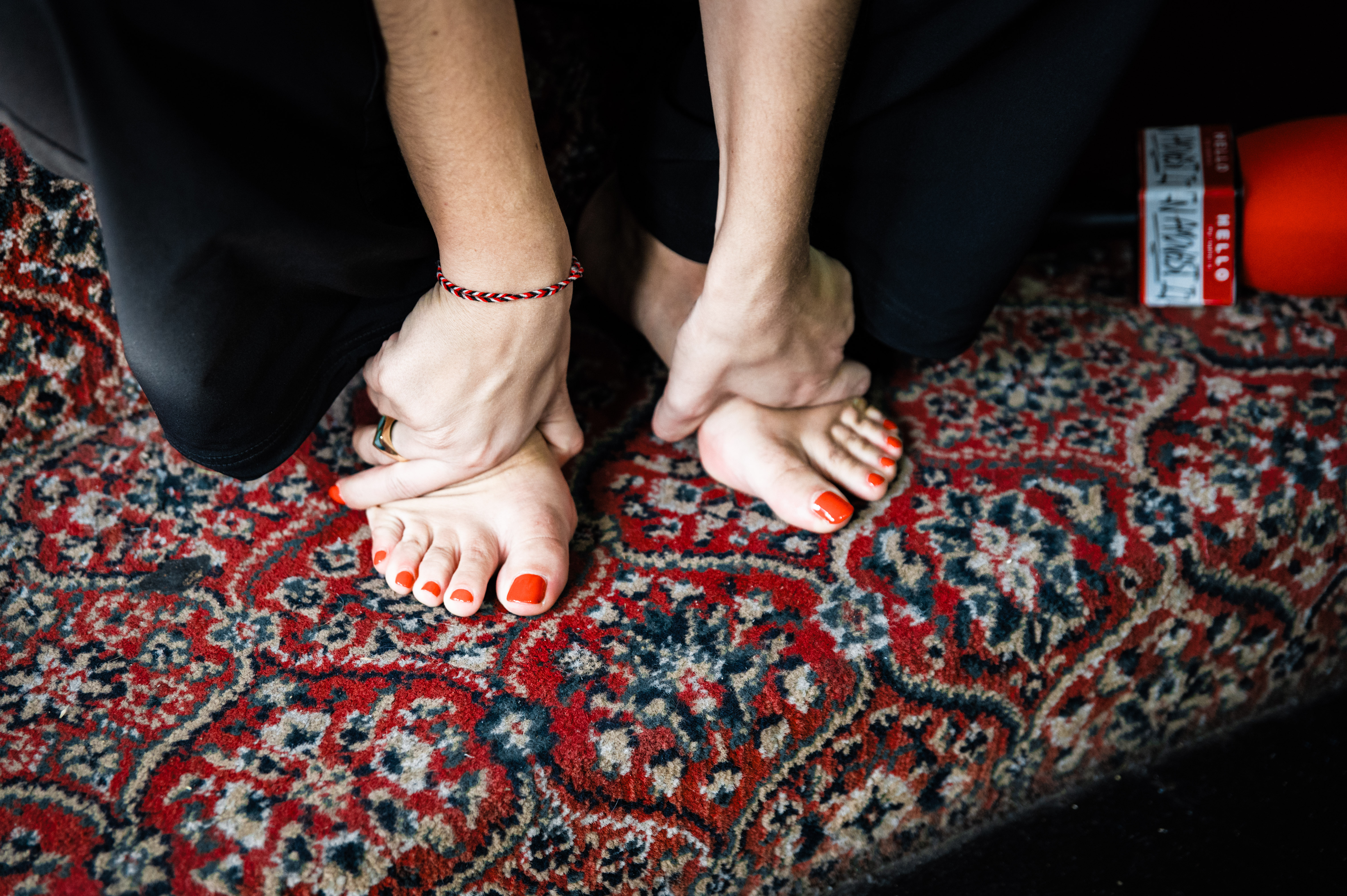 Bare feet on ornate red carpet with floral pattern.