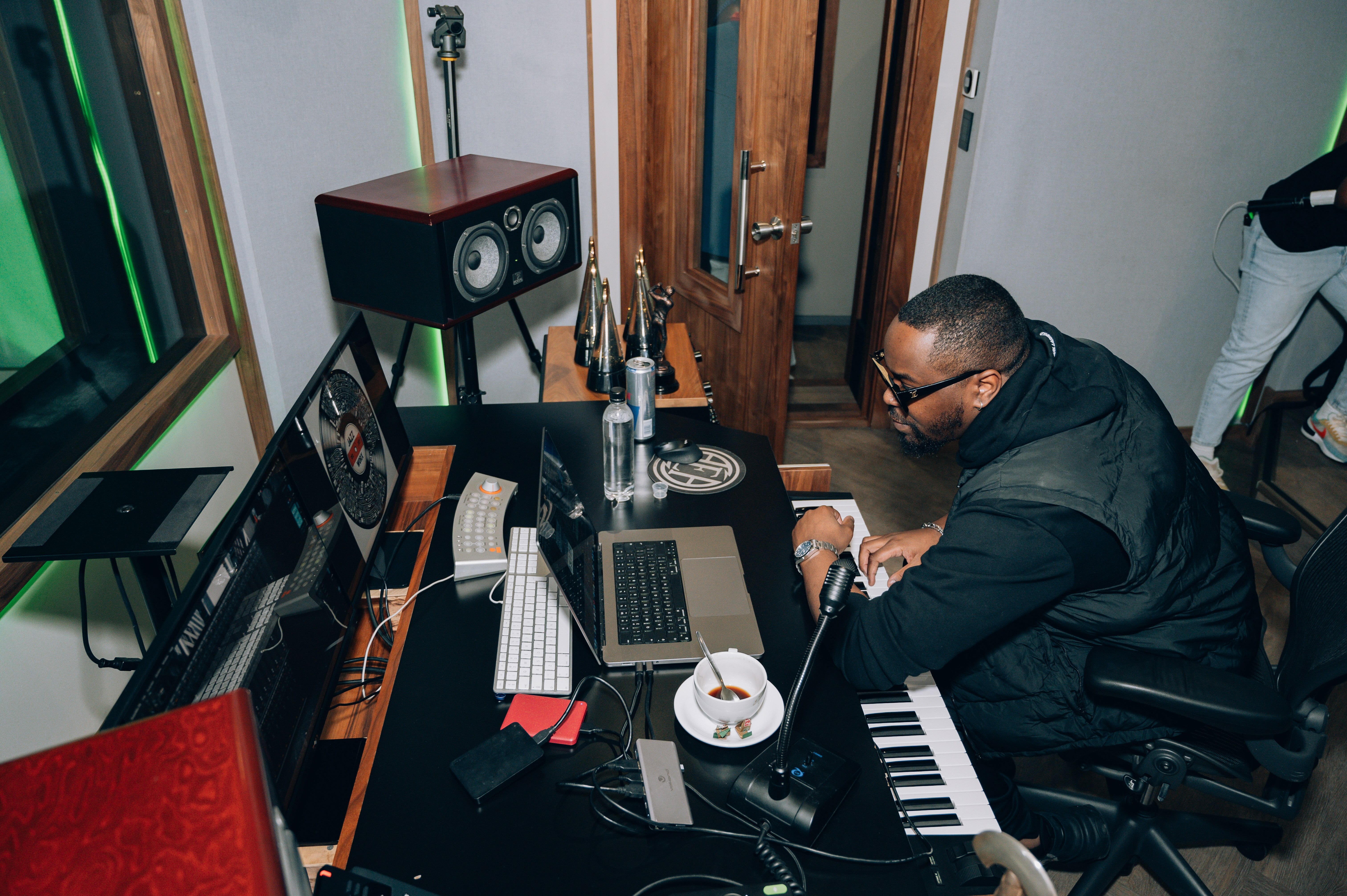 Home audio equipment, laptop, and piano keyboard on a desk in a cluttered home music studio