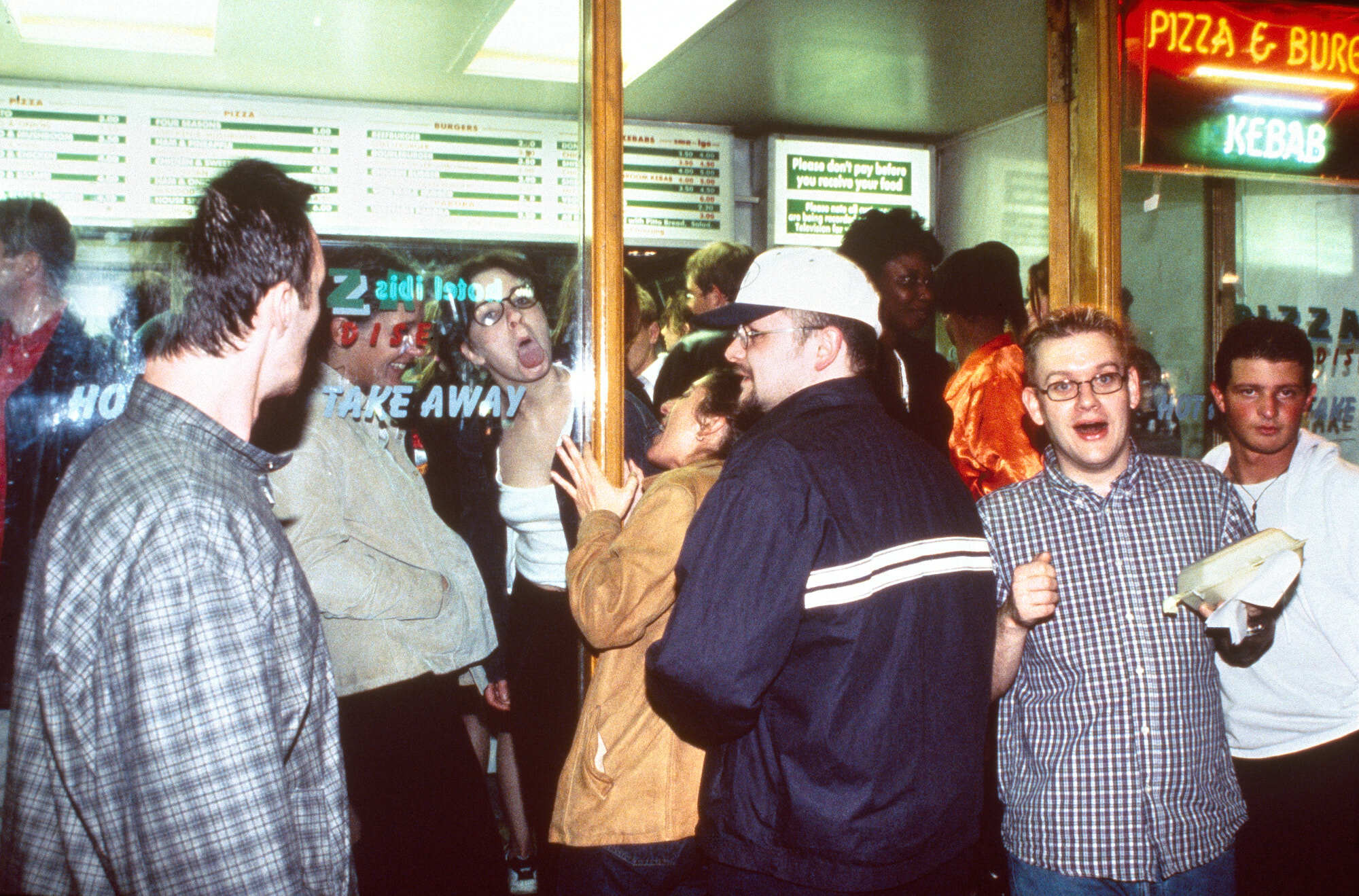 Busy fast food restaurant interior with people queueing and ordering at the counter.
