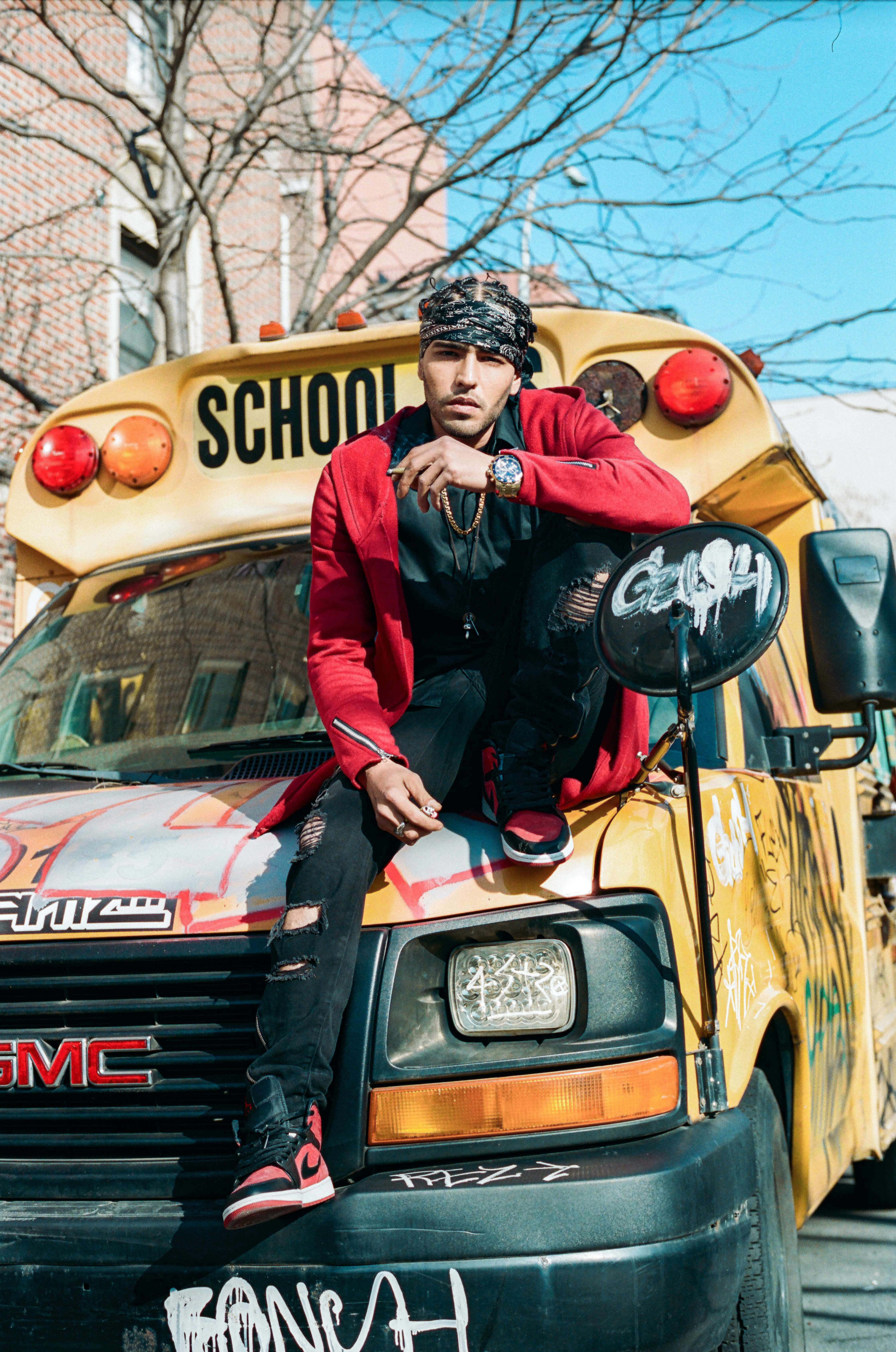 Person in red jacket and hat sitting on a yellow school bus with "SCHOOL" written on the side.