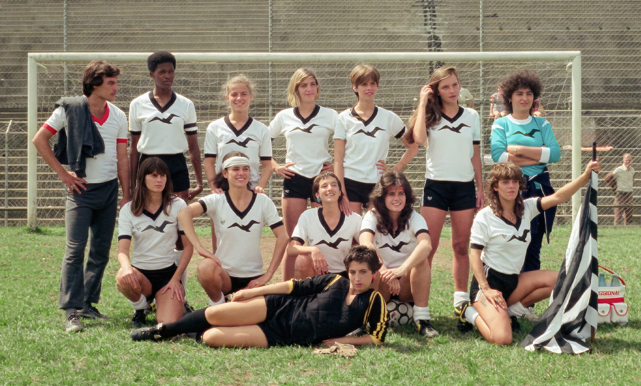 Group of young women in sports uniforms posing on a sports field.