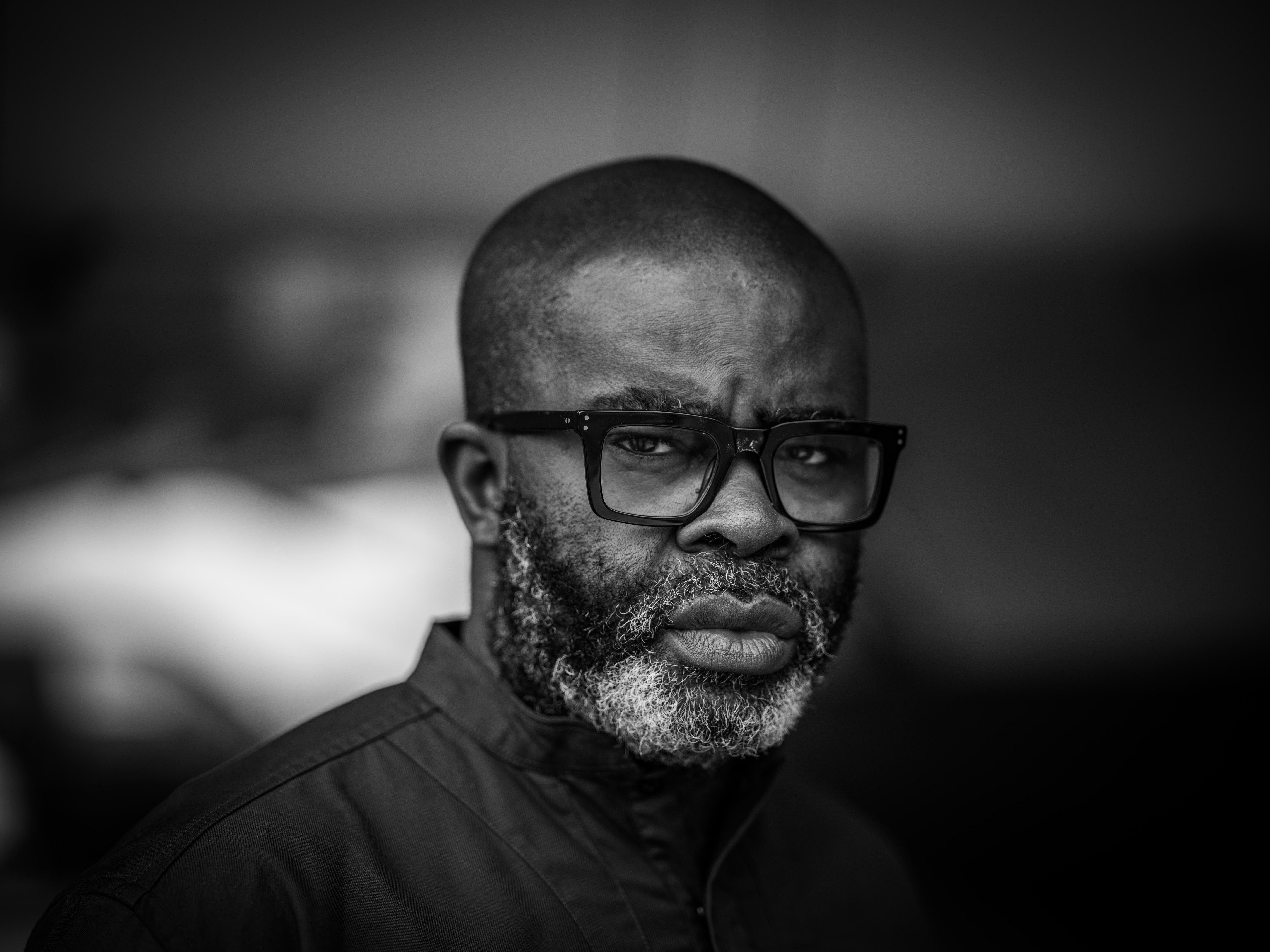 Portrait of a bald man with glasses and a beard, set against a blurred background.